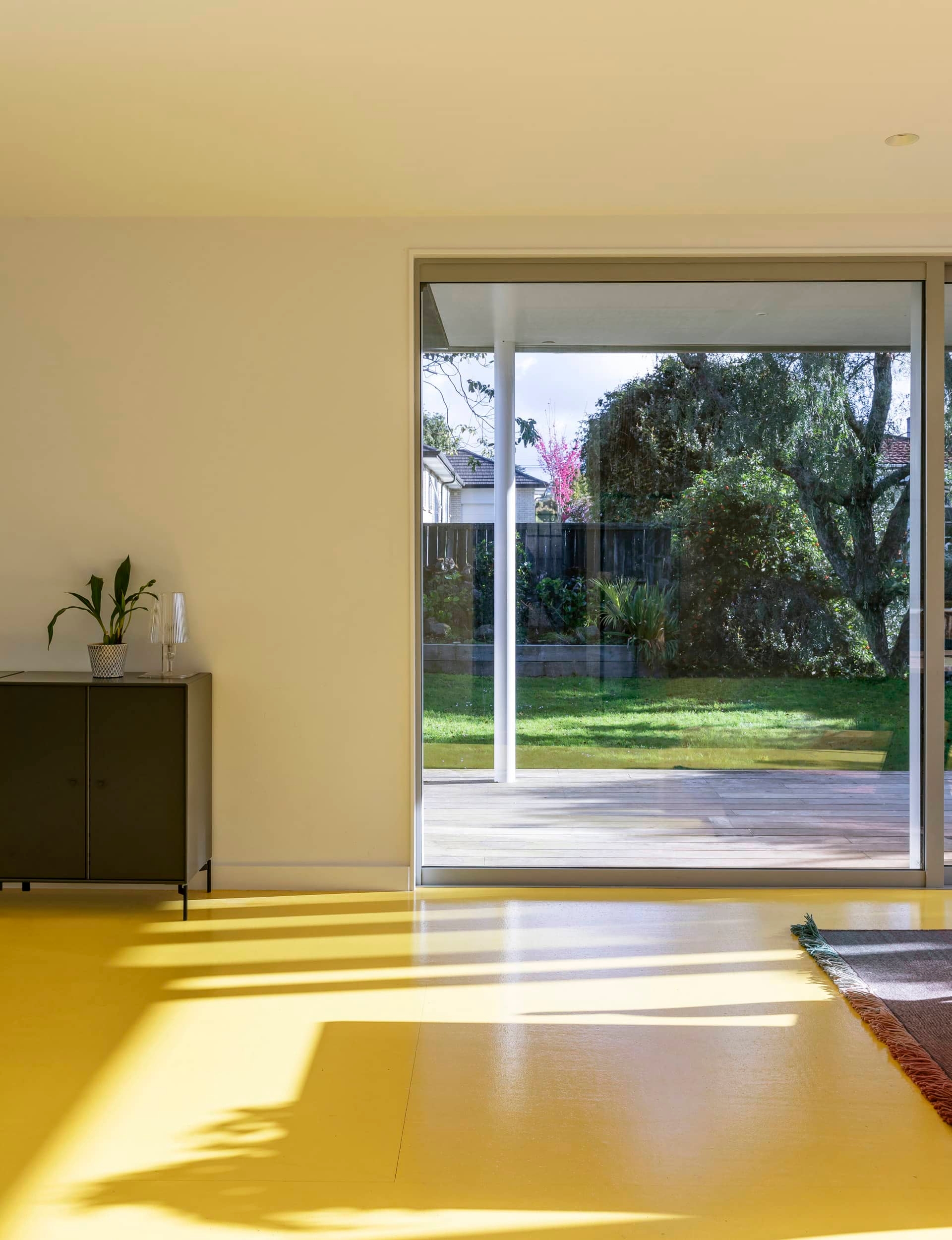 Open plan living room with a yellow floor and a ranchslider leading out to the deck and backyard