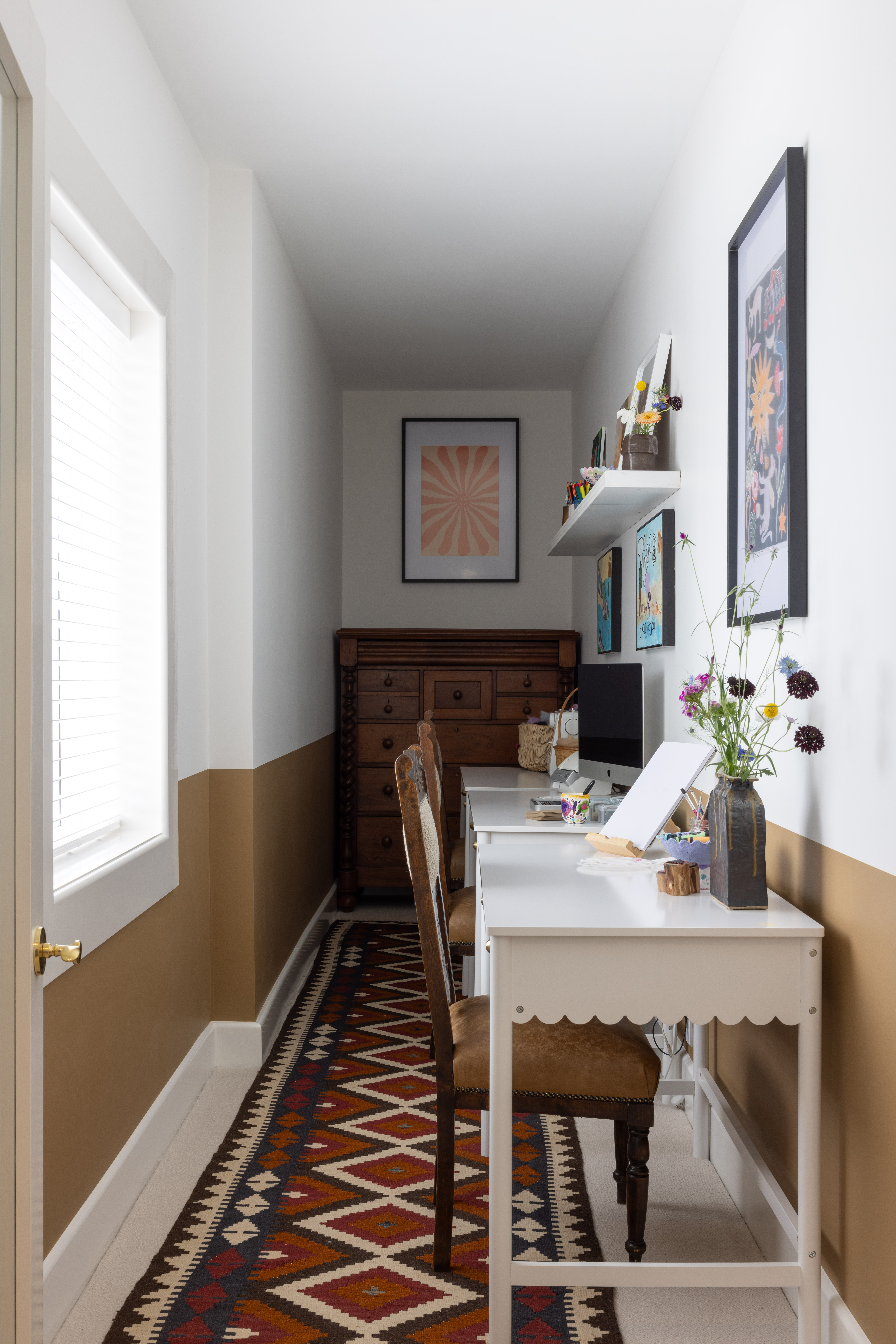 Originally a staircase to the lower level, this passage is now a craft space, with three stations set up on Mocka’s scalloped Maisie desks. “We were going to make it into storage, but I loved the idea of a dedicated space for creating,” says Isabelle. A datum line in Dulux Fantail wraps the room, where upcycled chairs were re-covered by Moto Trim using leftover leather from the kitchen banquette. A carpet runner from the Persian Rug Gallery adds colour, along with artworks including those by Adaline and Raphaela.