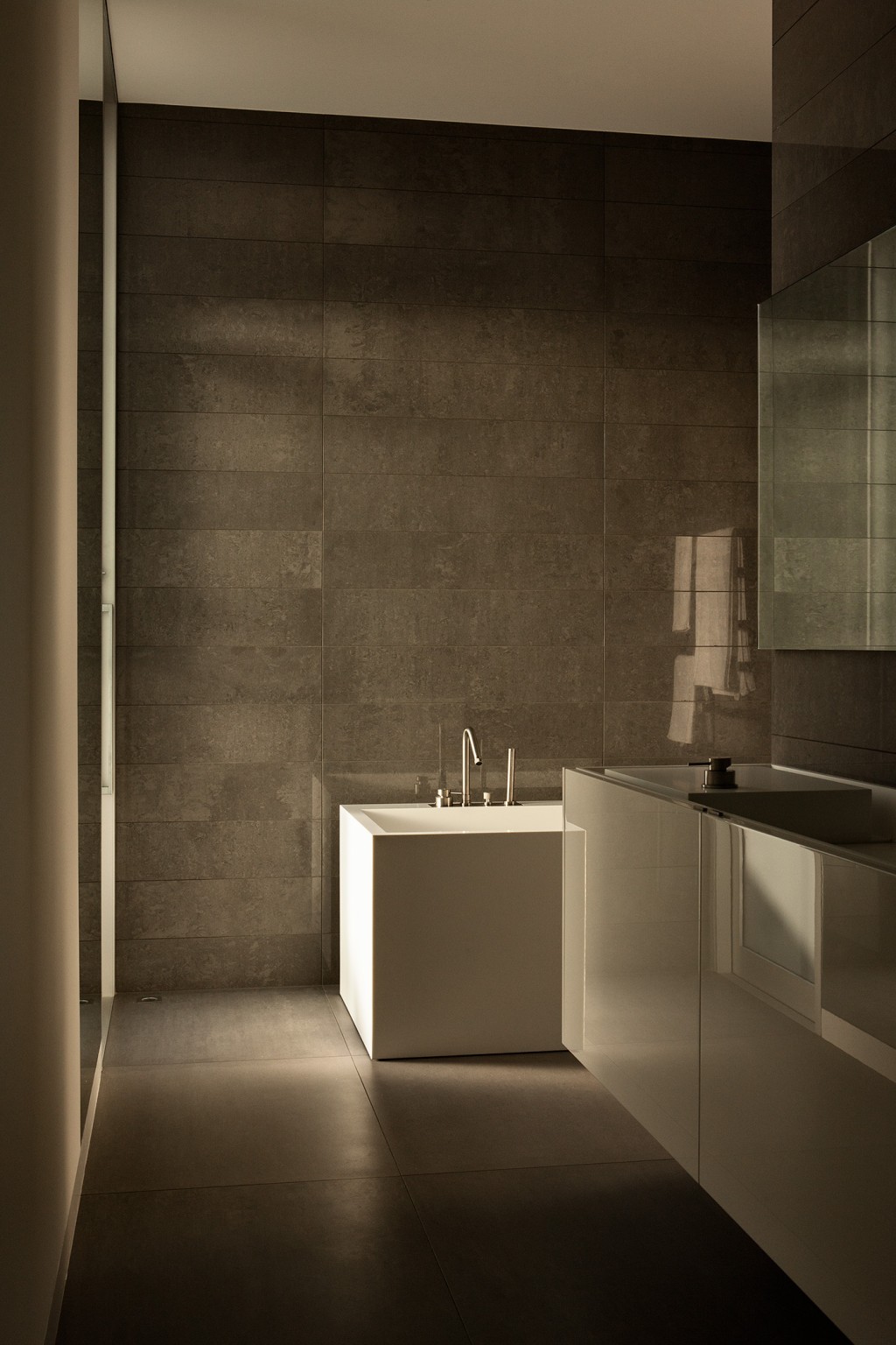 A moody bathroom featuring dark colors and tonal juxtapositions, characterised by sharp, crisp edges that enhance the interplay of light and shadow.