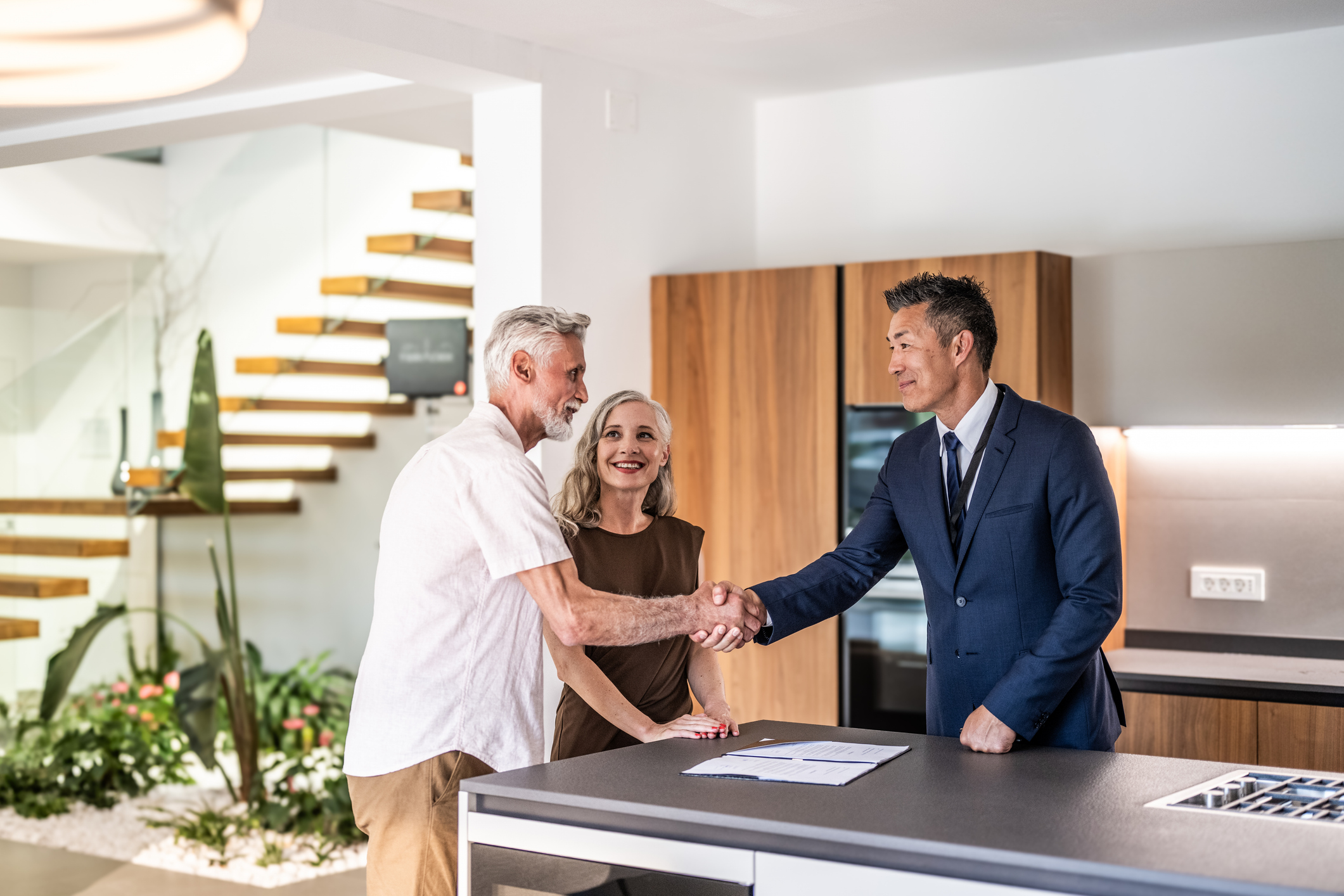 Couple shake hands with a property agent in a kitchen