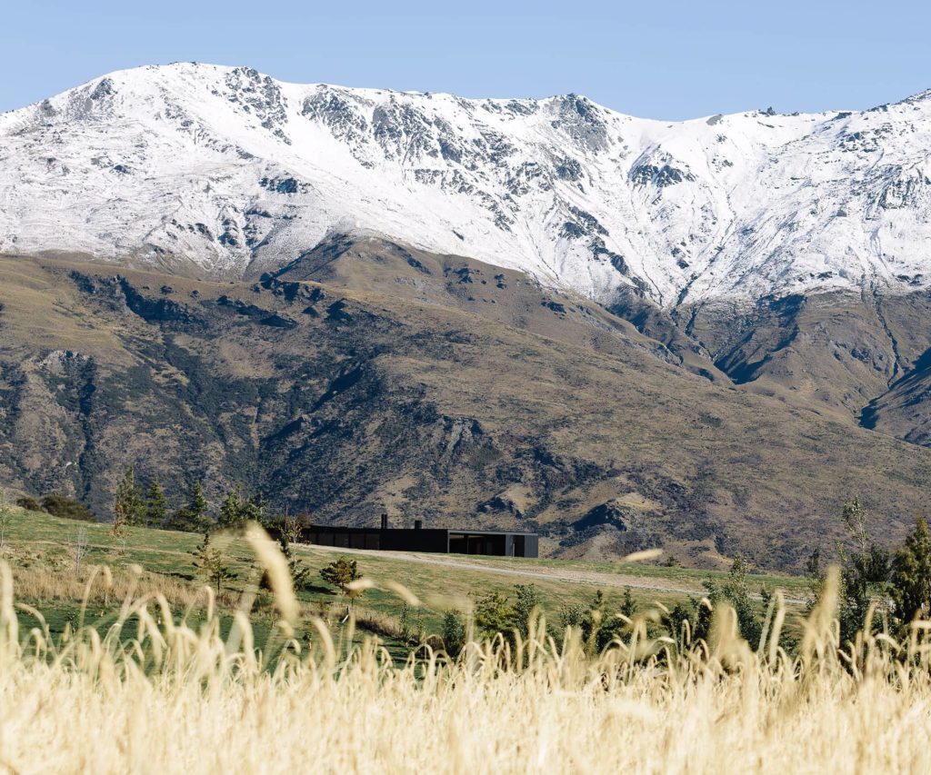 Long shot of house with snow-capped mountains behind it