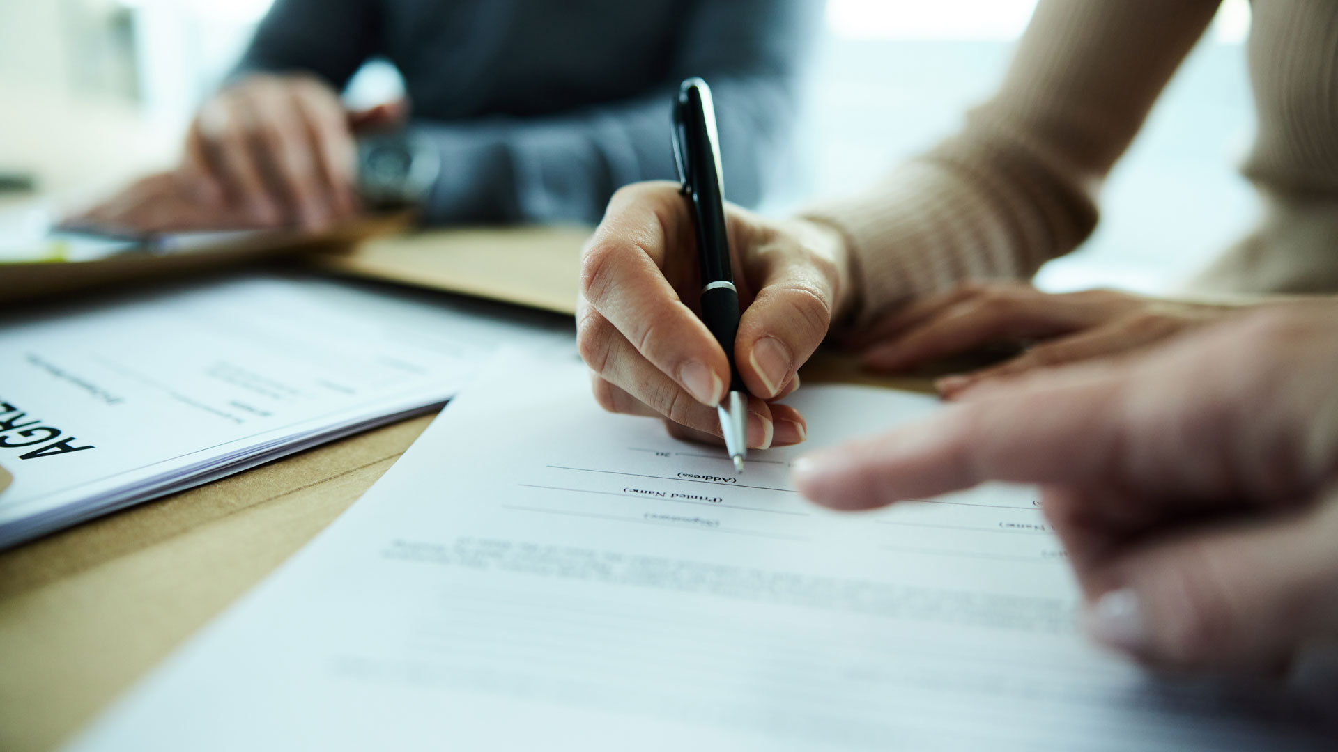 A home owner signing a sale and purchase agreement to sell their home.