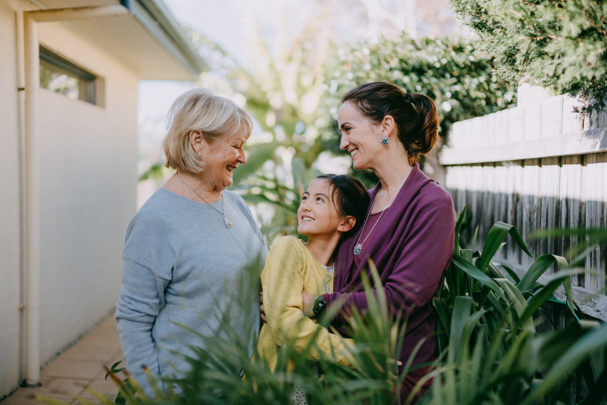 Mother, daughter and granddaughter stand in the garden