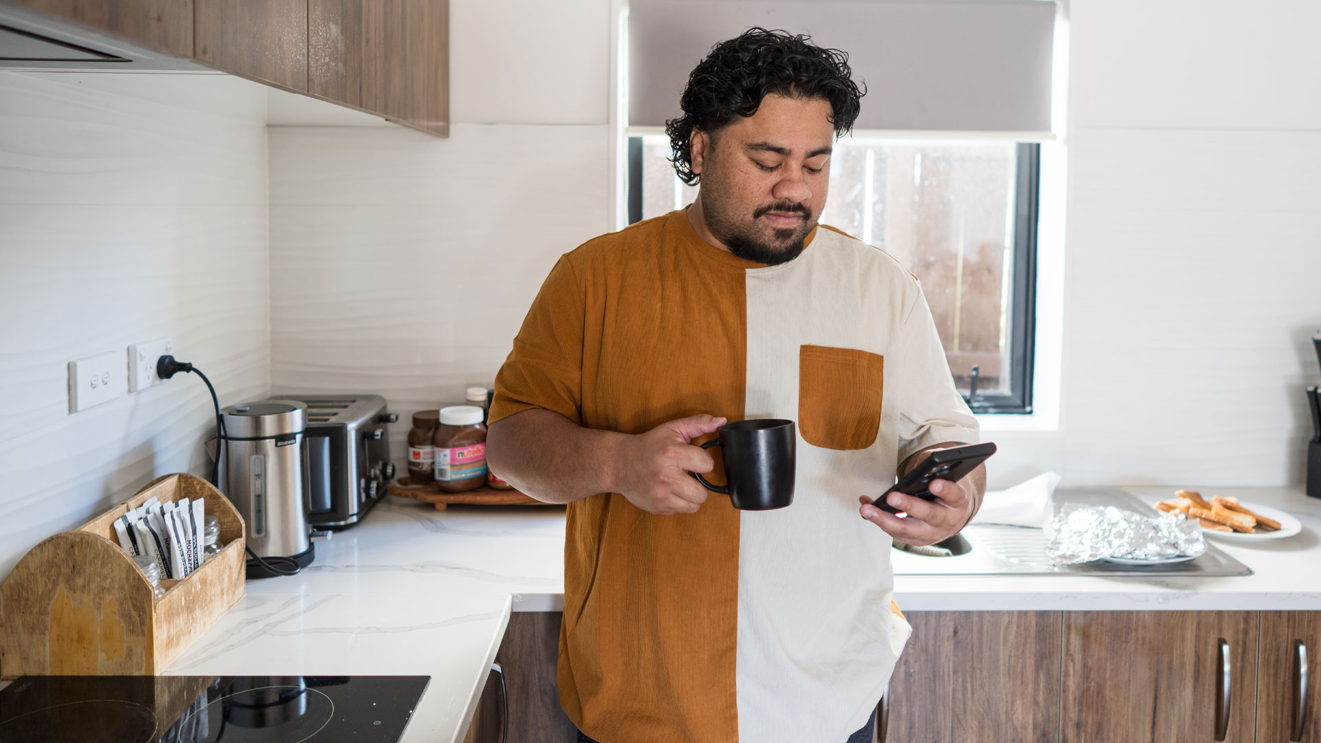 A NZ man at home reading a text from someone who wants to buy his property.