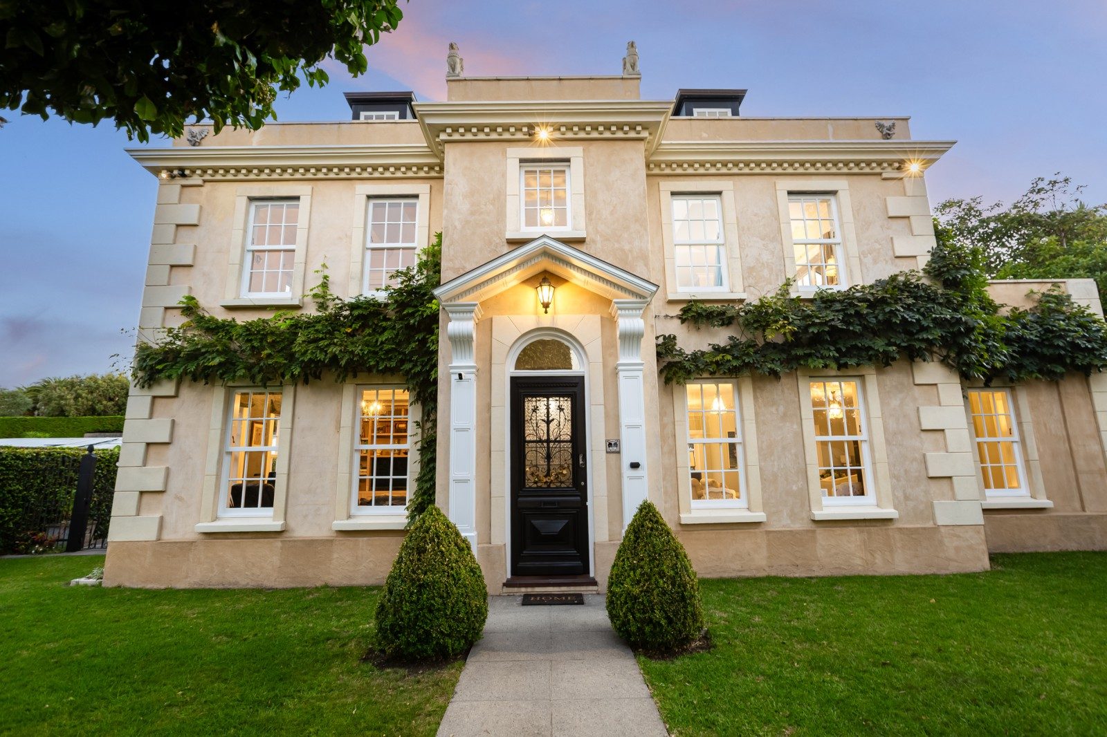 A beautiful Georgian home with symmetrical windows on either side of the front door. Vines grow across the middle of the house.