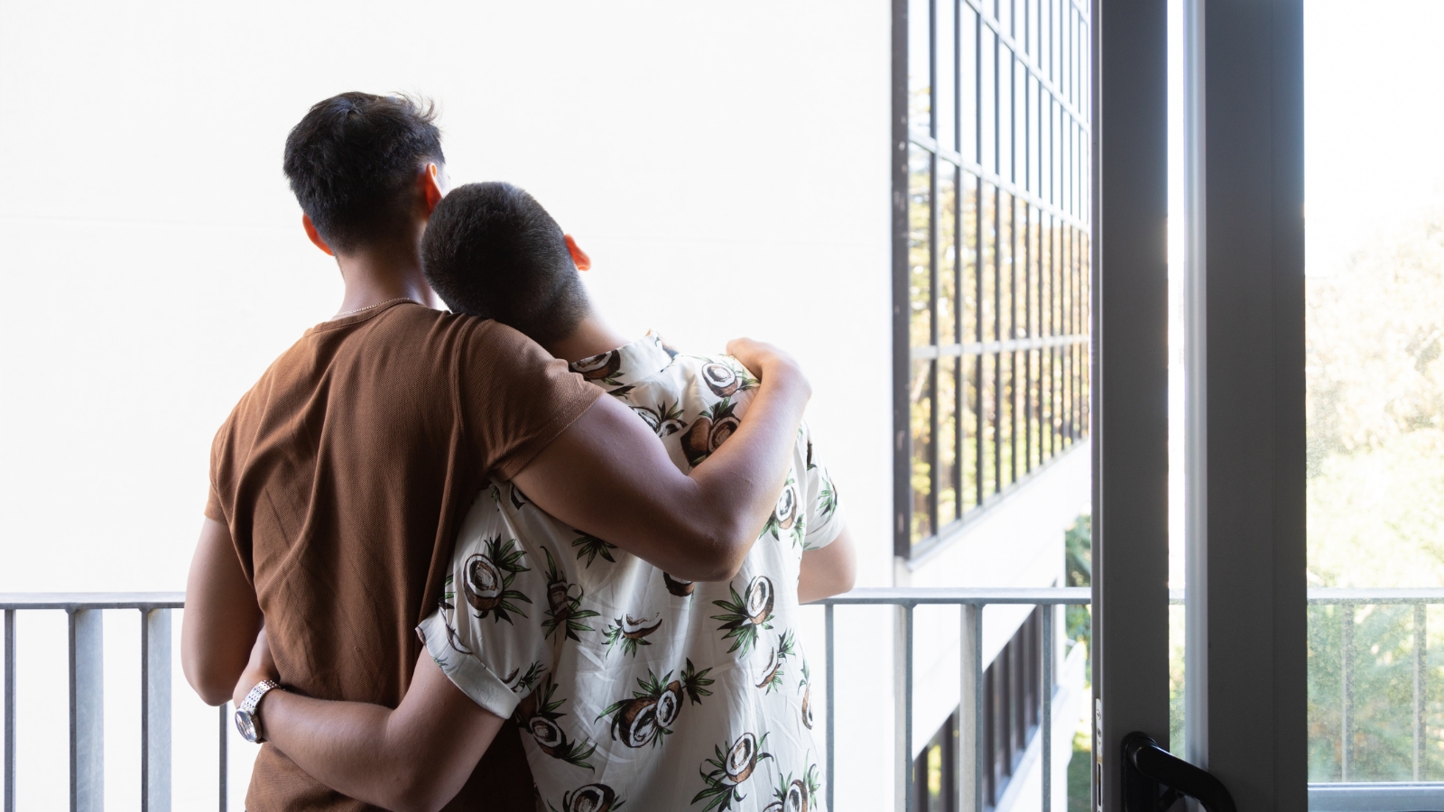 Couple hugging and looking off their balcony. 