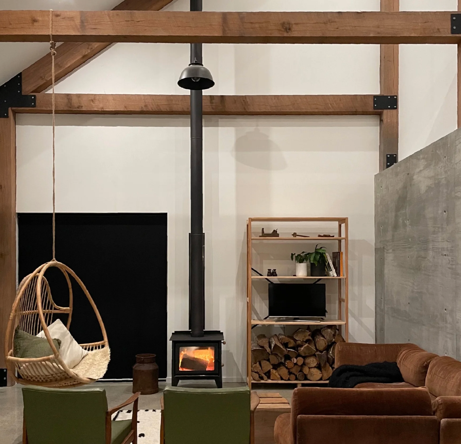 Lounge in the 2022 Rural Home of the Year, Black Ridge by Toby Chapman-Smith and Benjamin Conner, featuring a modular sofa and occasional chairs with views of kererū among the trees.