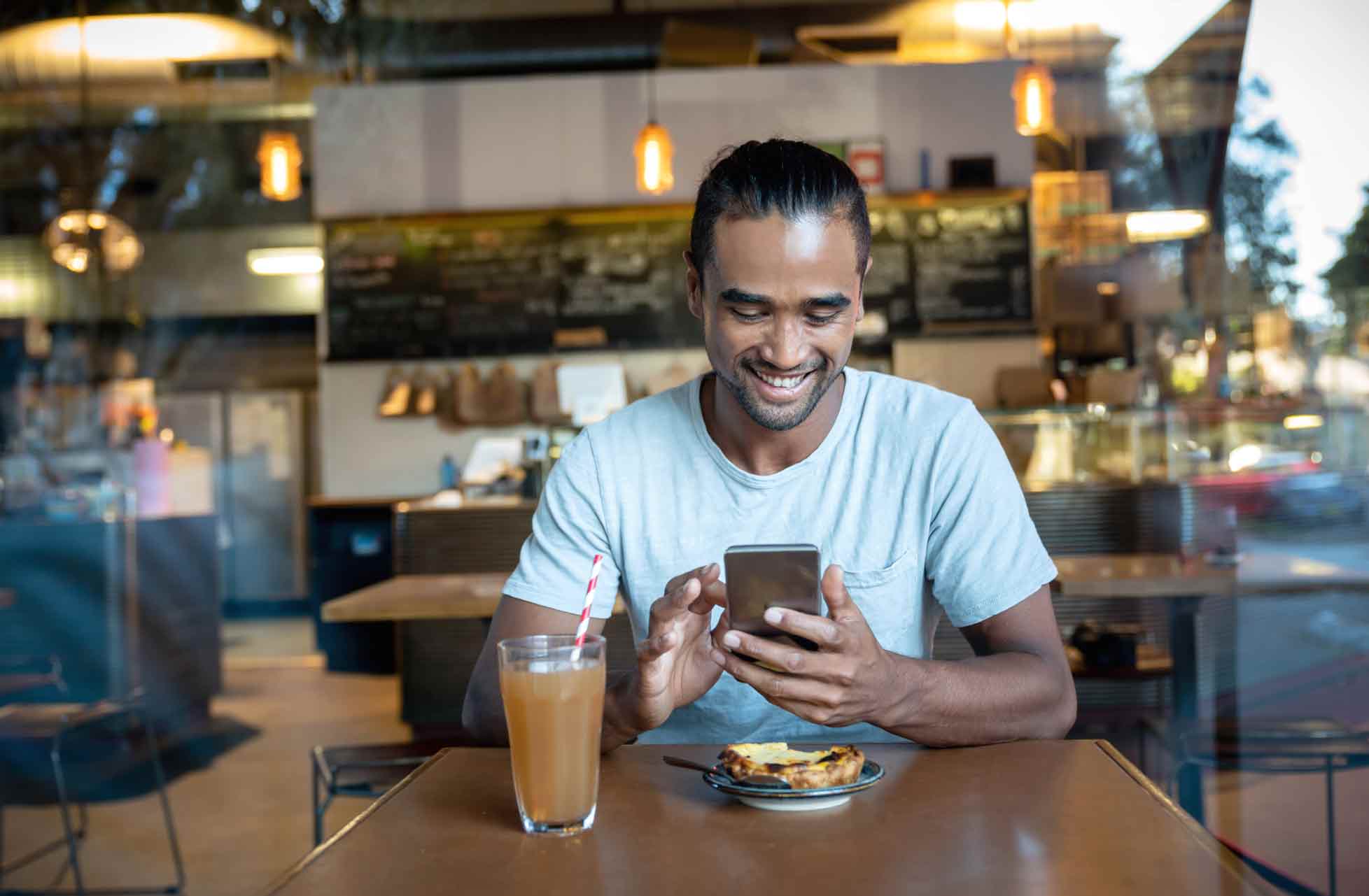 Person shopping on Trade Me phone on their phone in a cafe with a panini and apple juice.