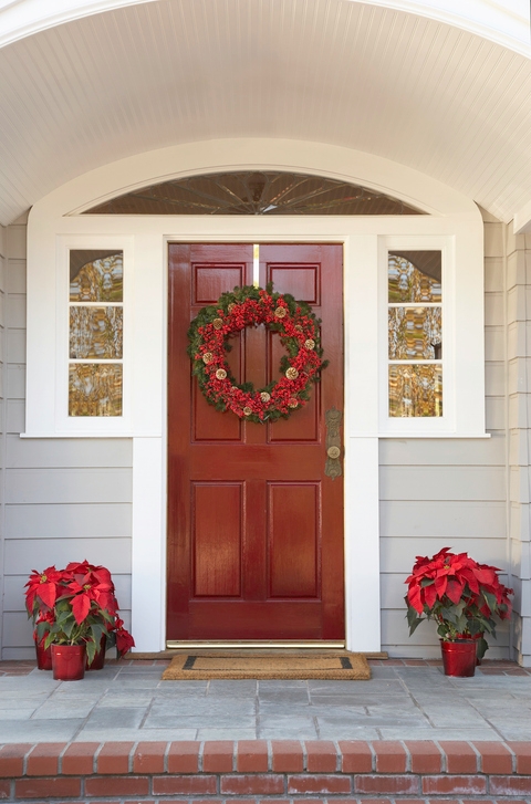 A front door adorned with seasonal decorations, including a festive wreath and a welcoming doormat.