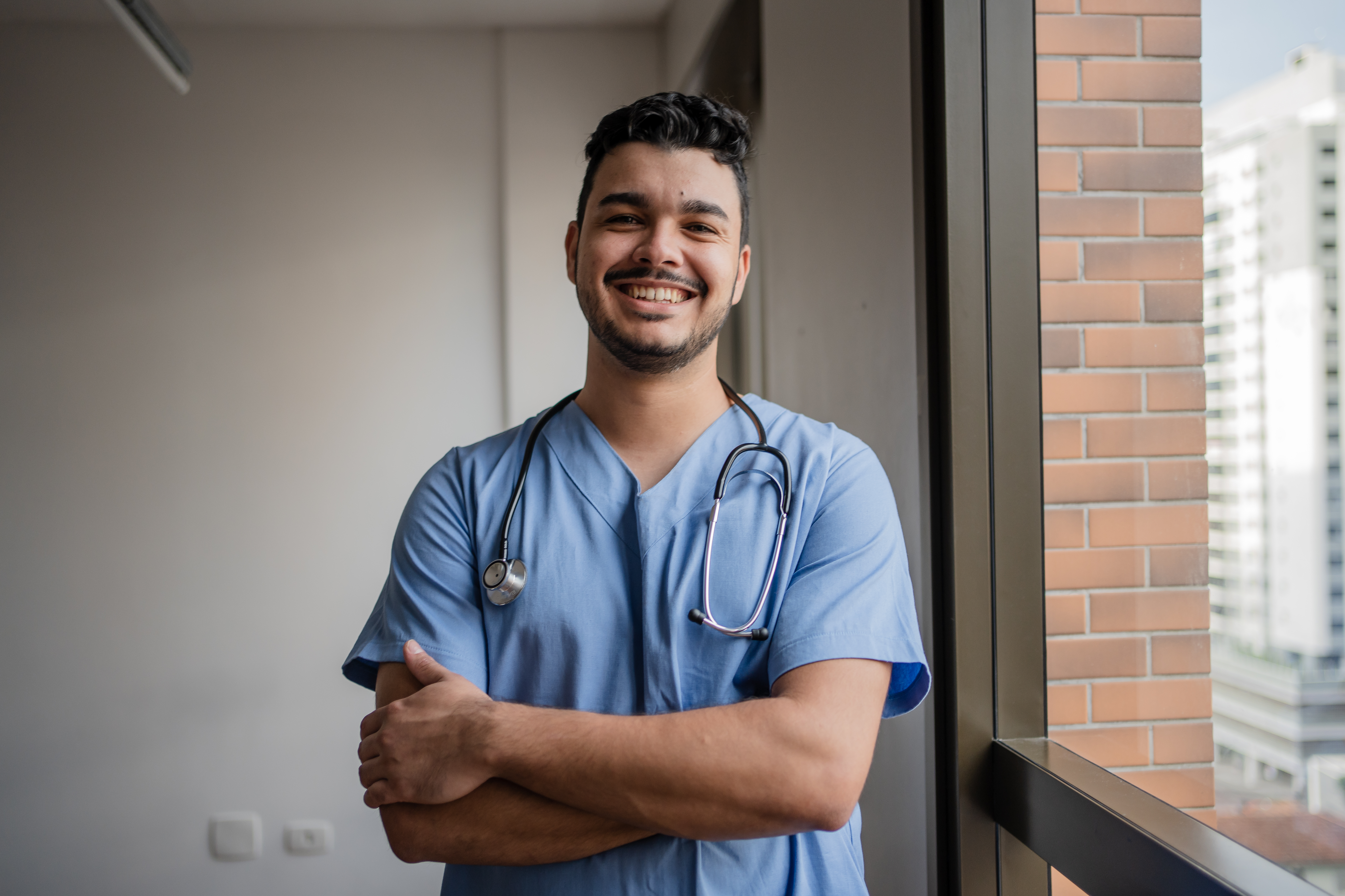 Male nurse standing in a hospital with arms crossed