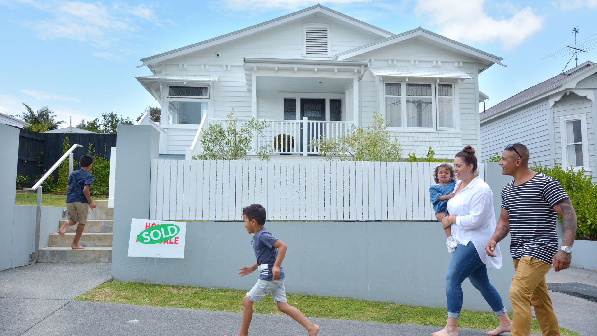 Timber clad houe on a street in Auckland, New Zealand. A new family is moving in after buying the home on Trade Me Property.