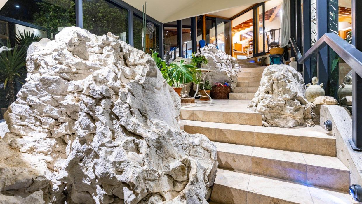 Stairs at the entry climb around large limestone boulders