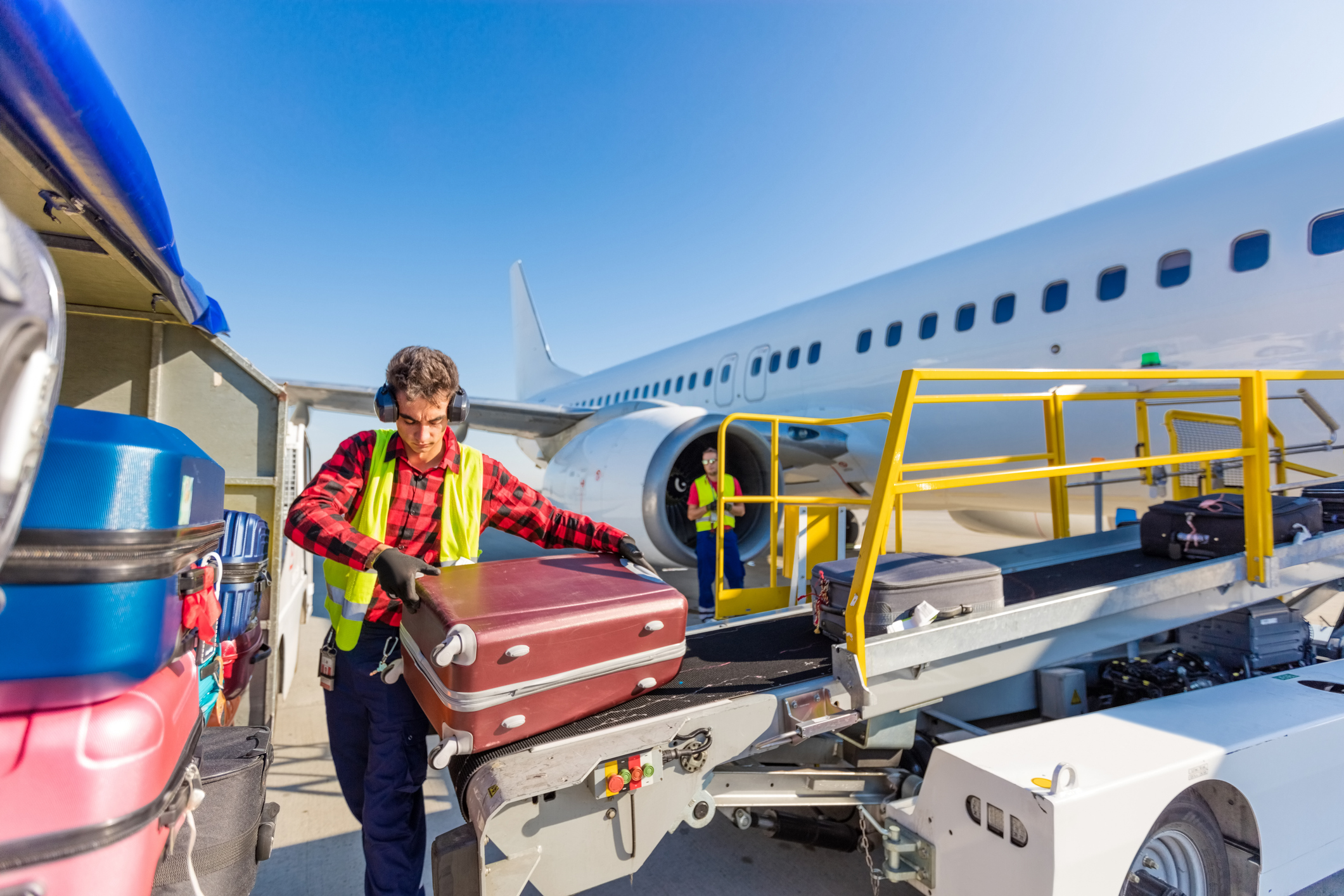 Young male baggage handler unloading luggage off a plane
