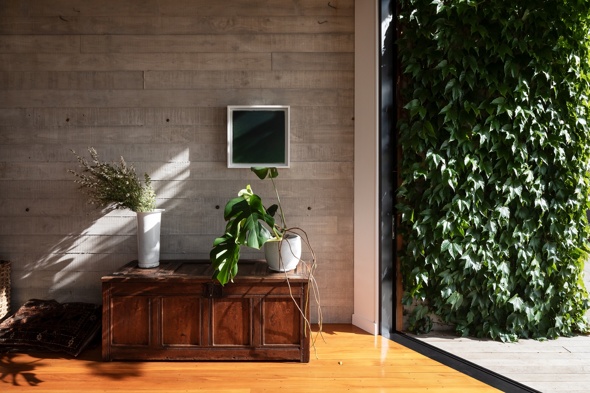 Living room with large window that looks out on to a hedge.