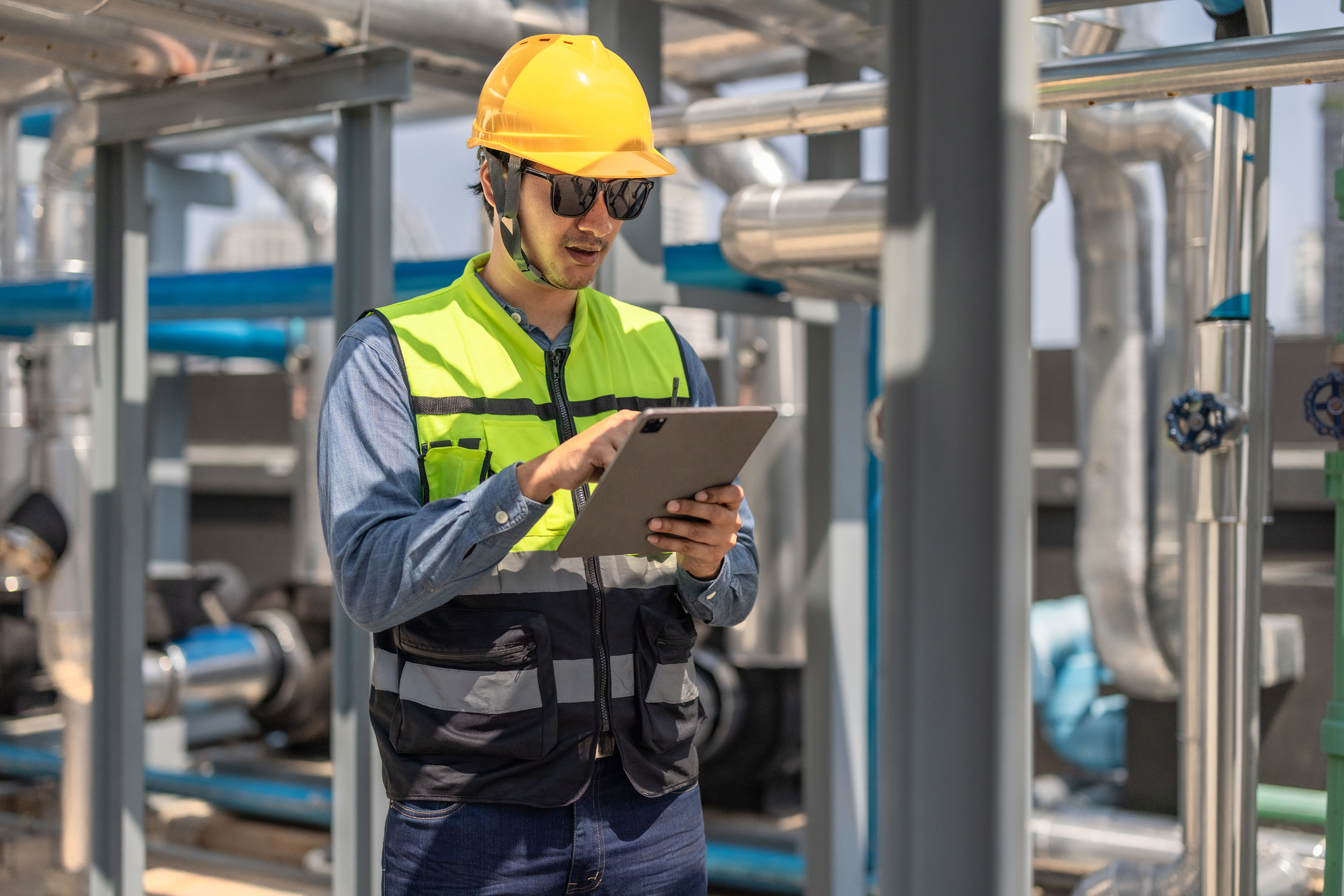 Plumber looking at ipad surrounded by pipes