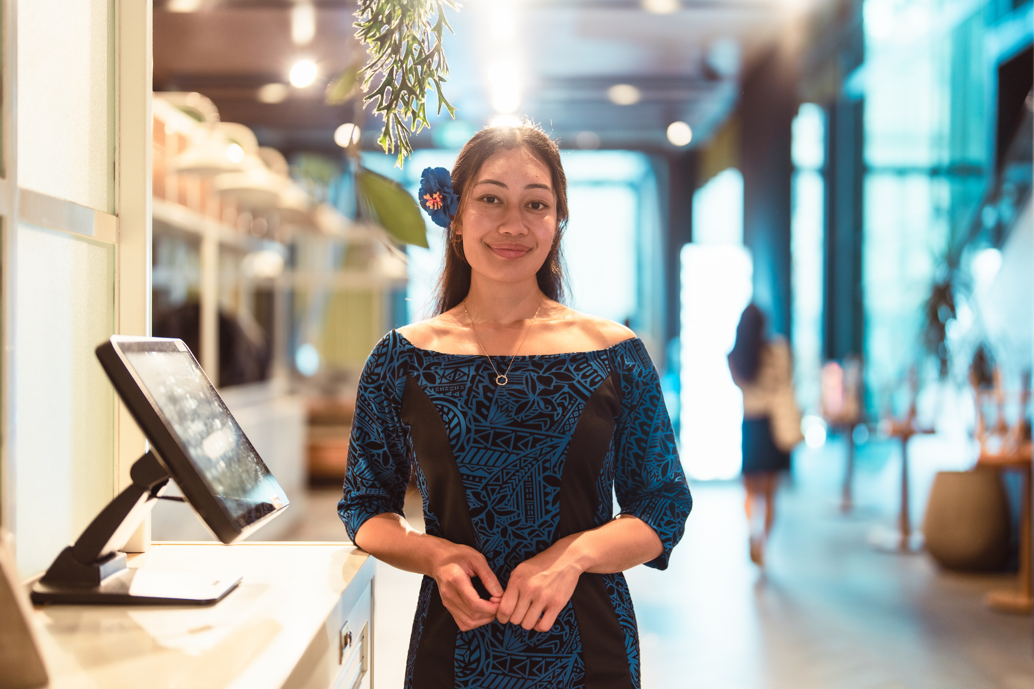 Young female retail worker standing in front of retail store.