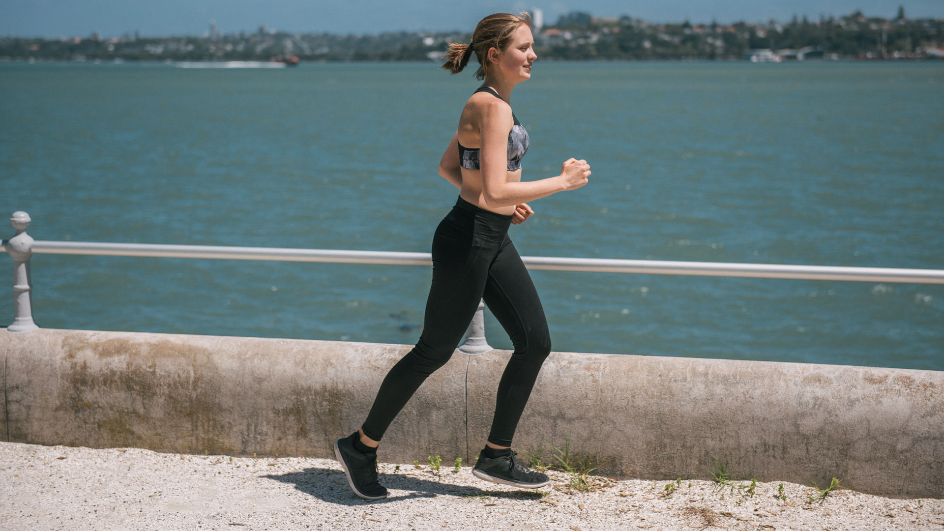 Woman running along the ocean front in NZ.