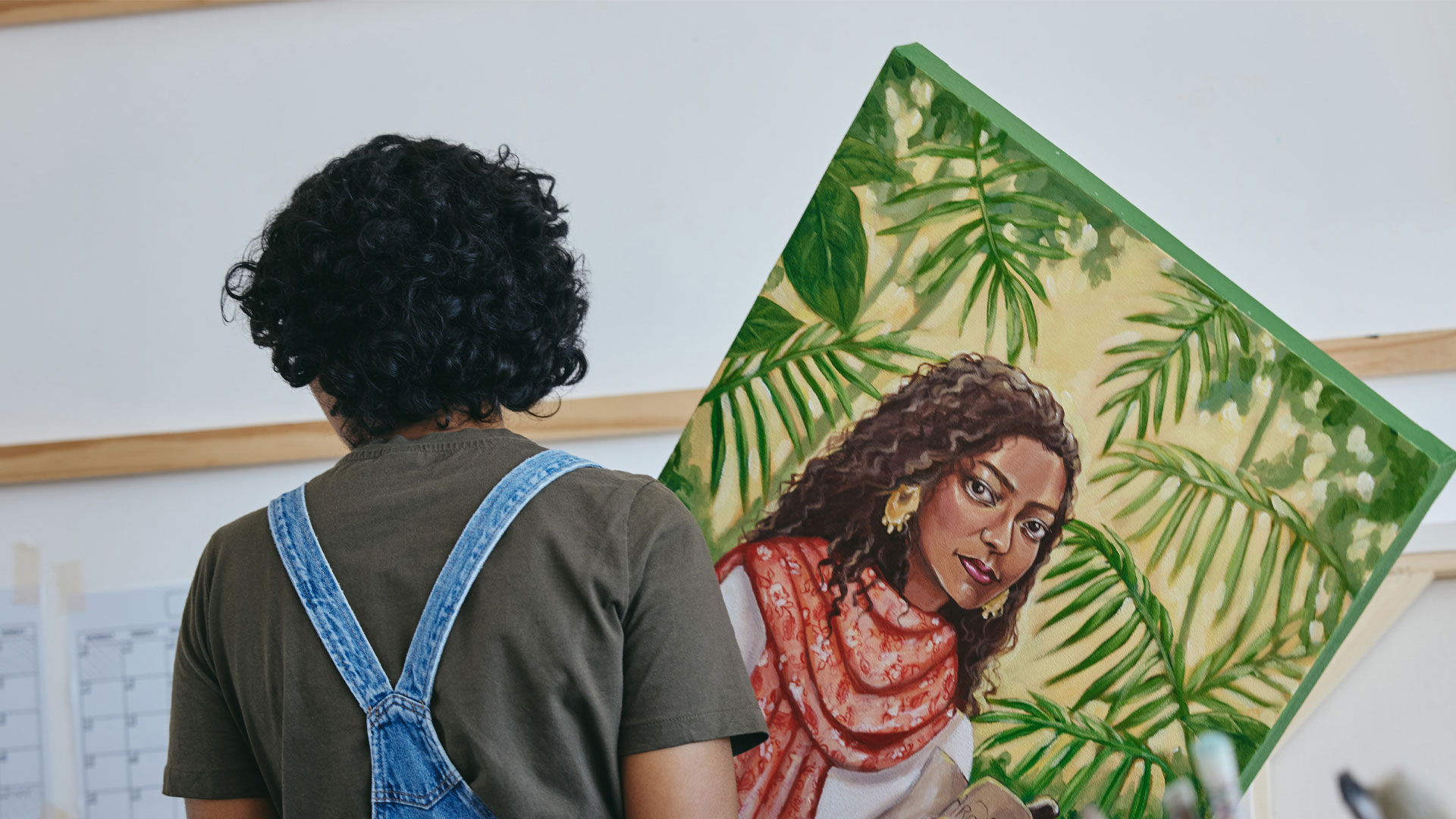 Artist holding a painting that they are about to display on a wall in a gallery.