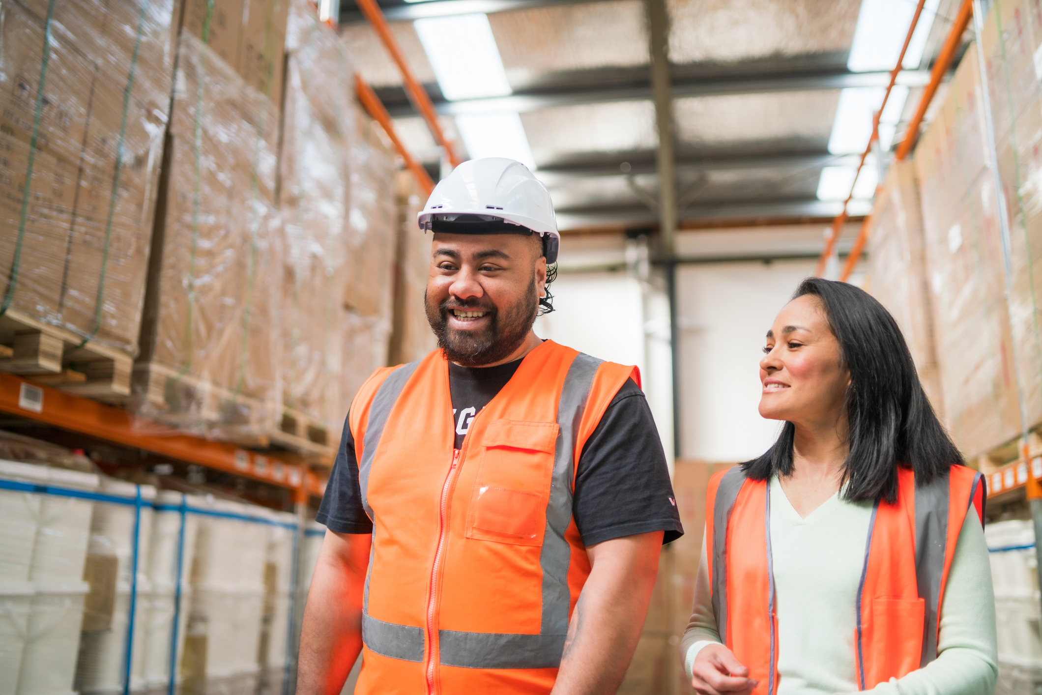 Two Kiwi warehouse workers chatting while walking through the warehouse
