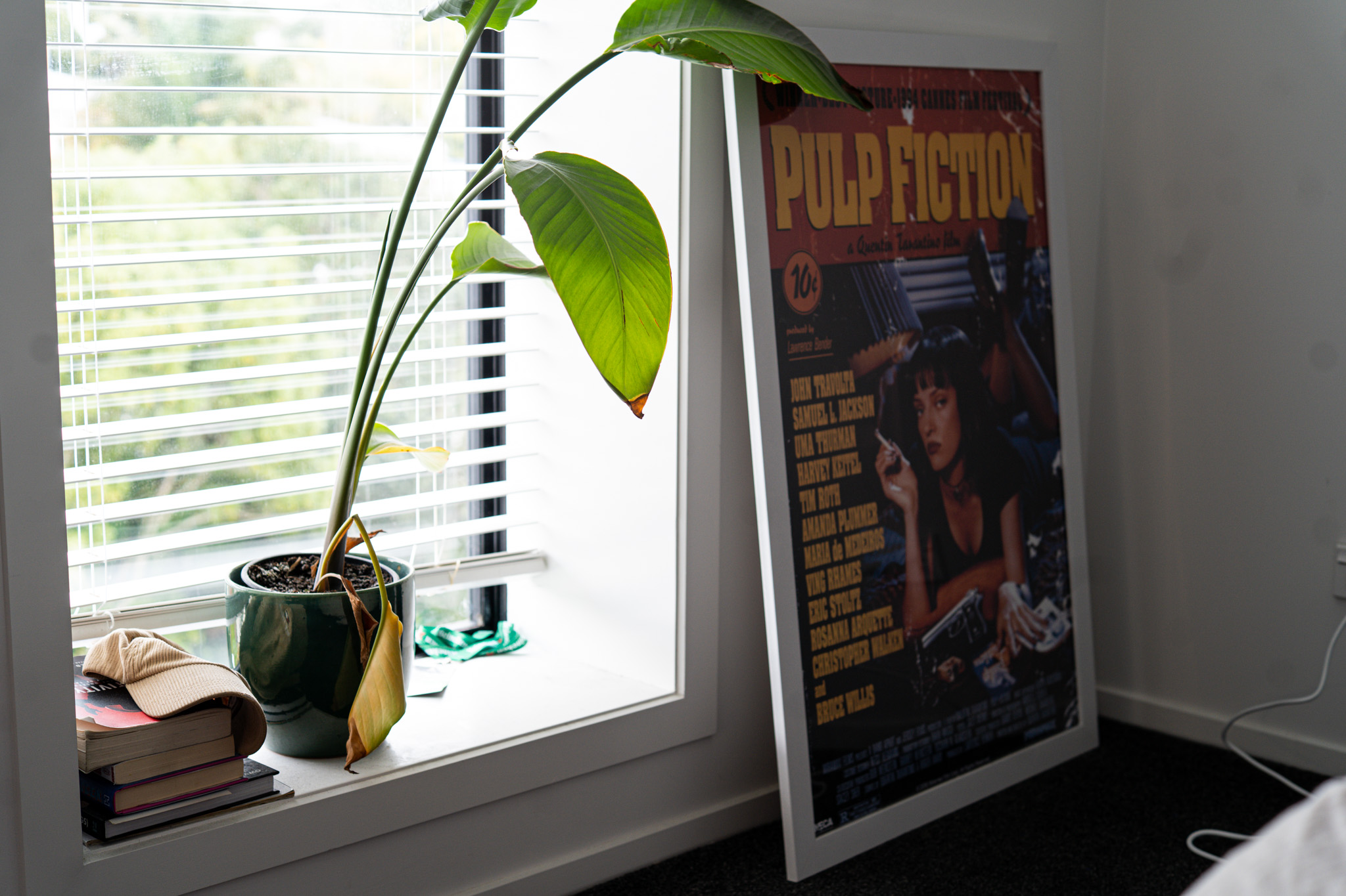 A framed Pulp Fiction poster and plant in Joey's bedroom
