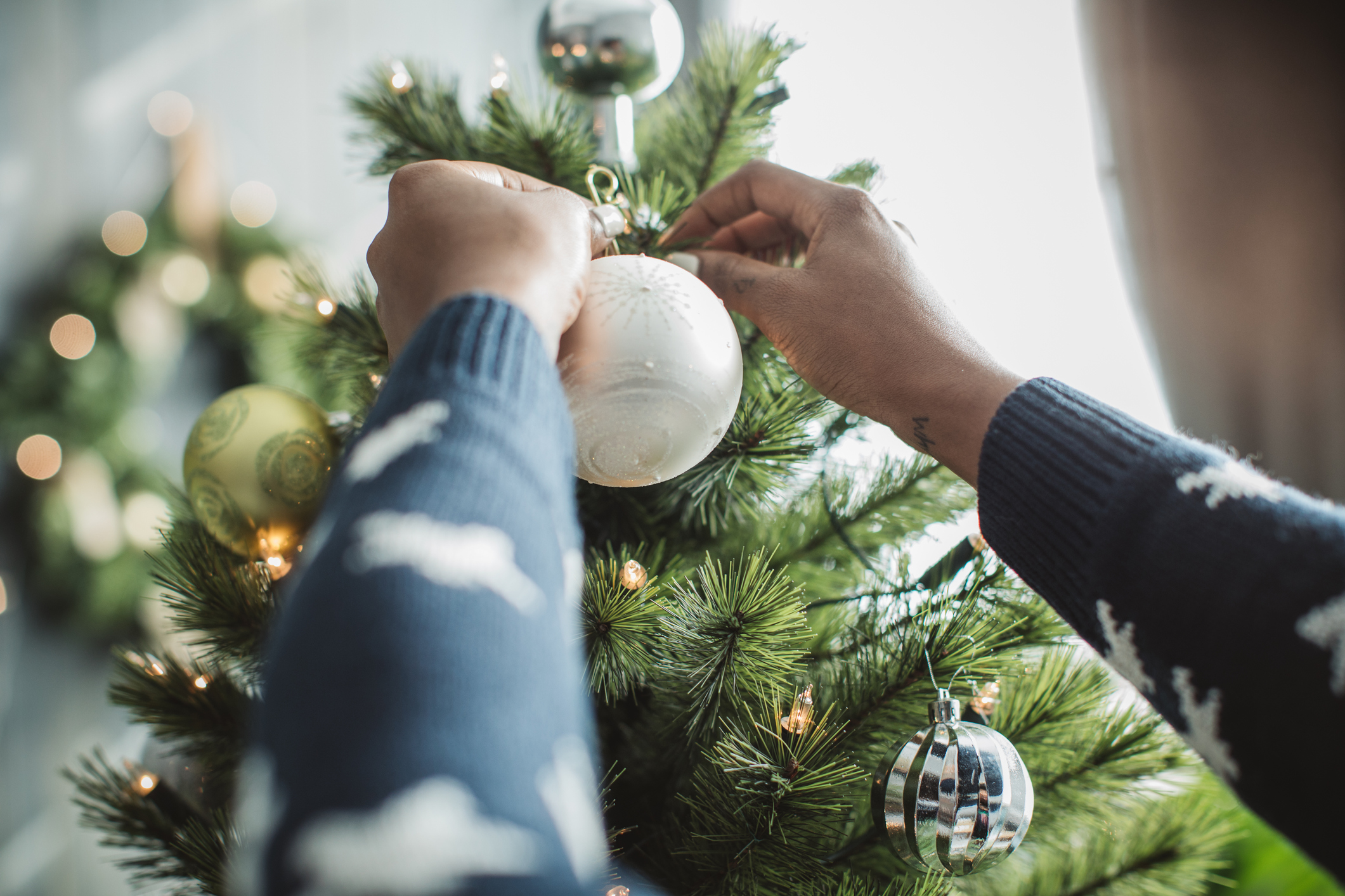 Person putting decorations up on a real christmas tree