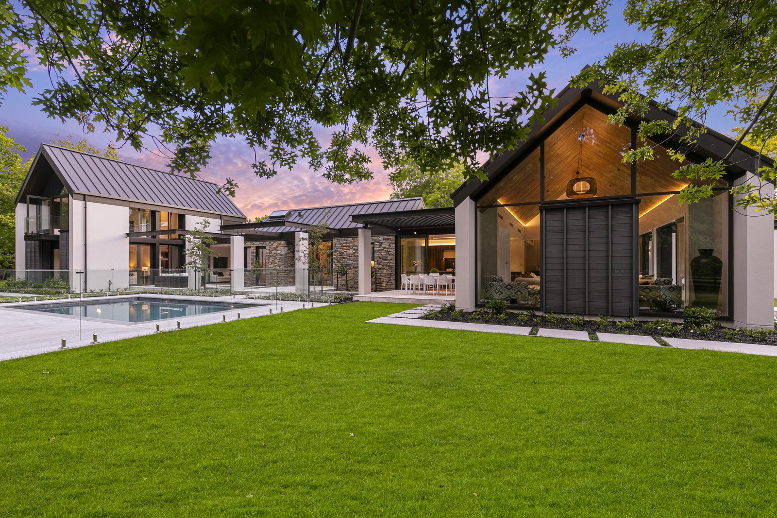 Green lawn, pool and beautiful white, black and brick home.