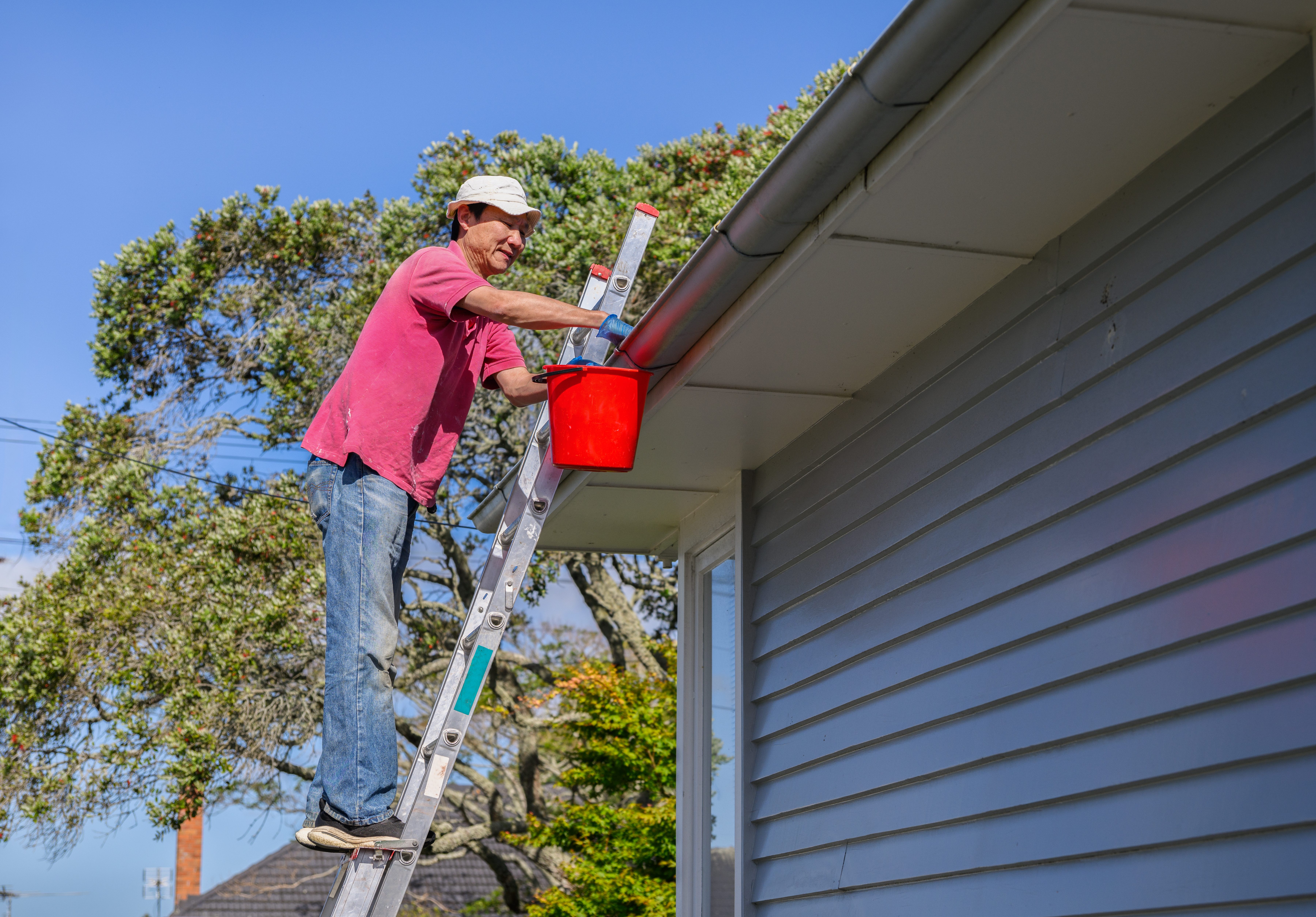A man clears his gutters at home