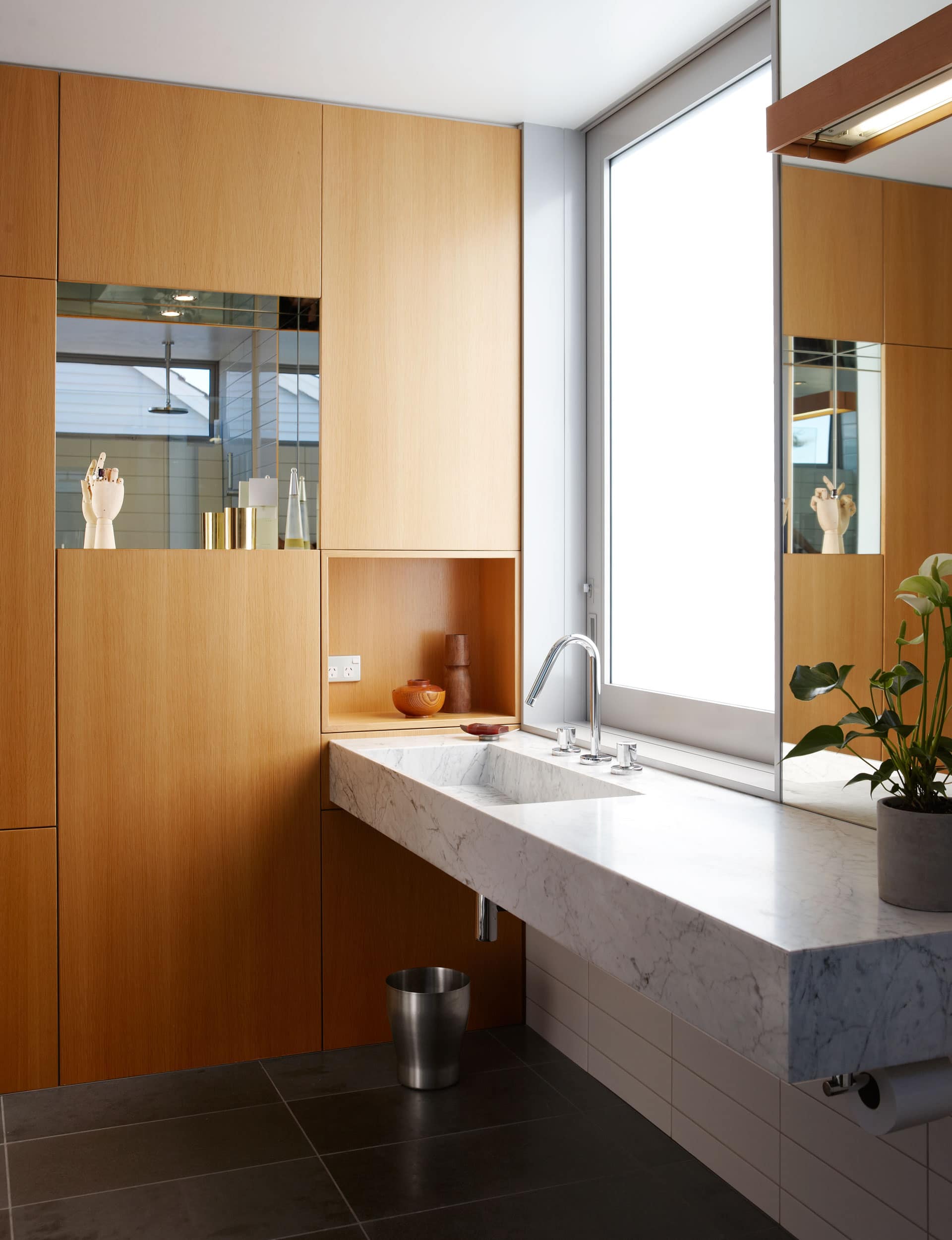 Modern bathroom with integrated vanity. Wood and marble complement each other whilst the plants and ornaments pull the space together.