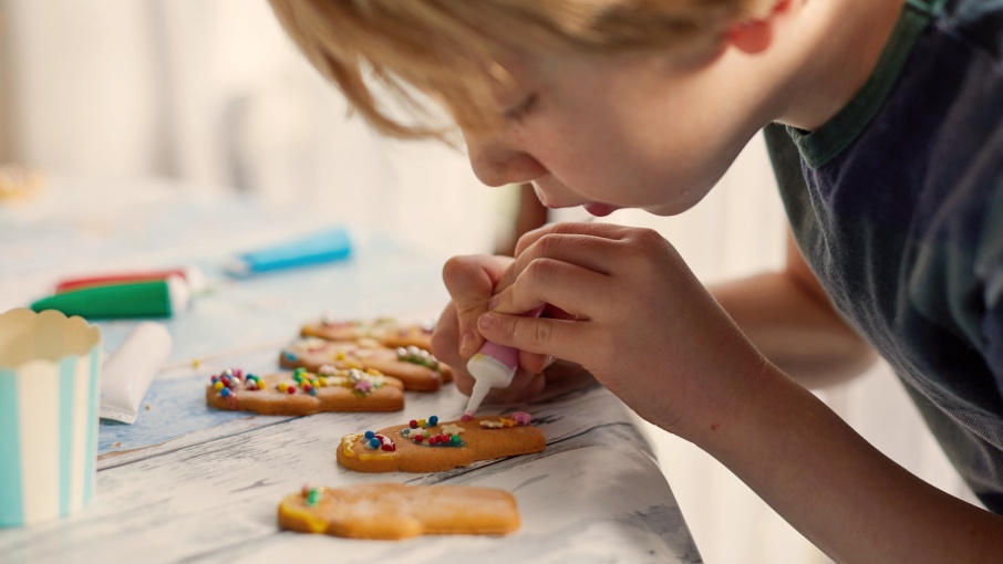Young boy creating gingerbread cookie cutter characters at home.