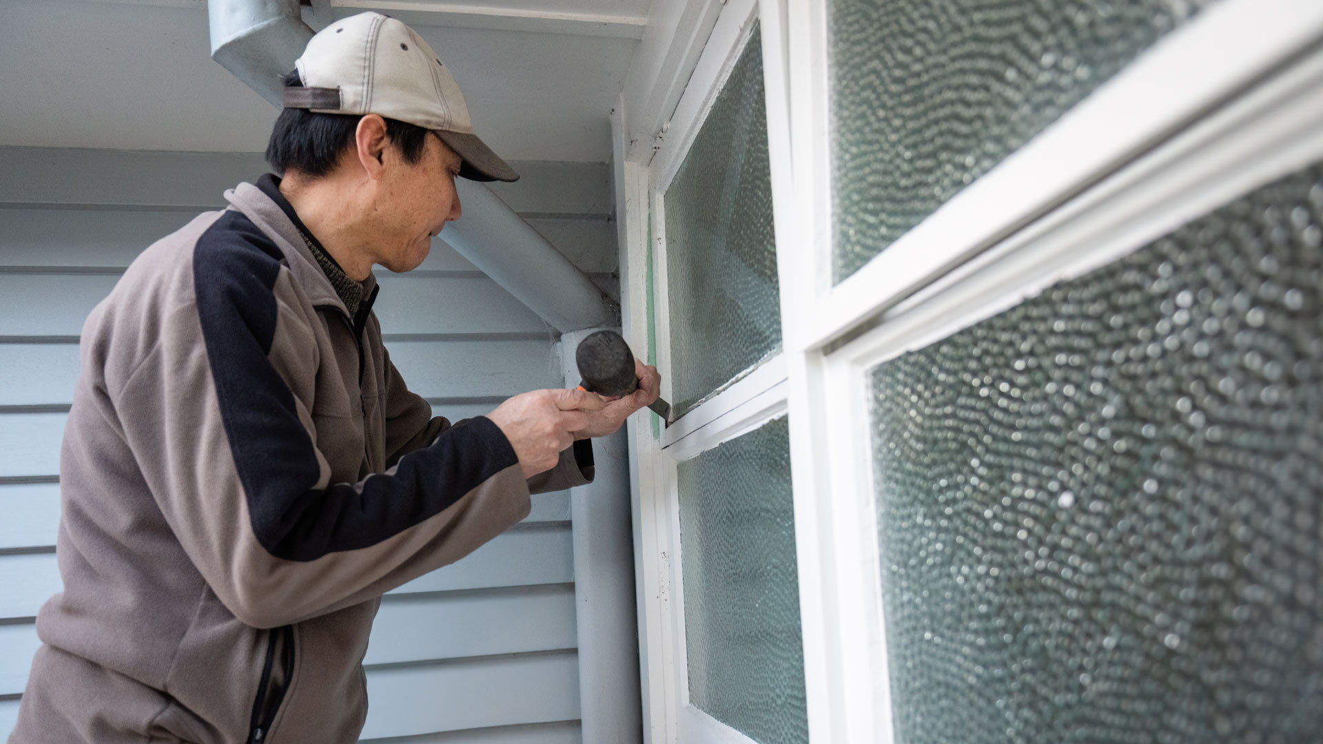 A man doing some renovation work on an exterior window on his property.