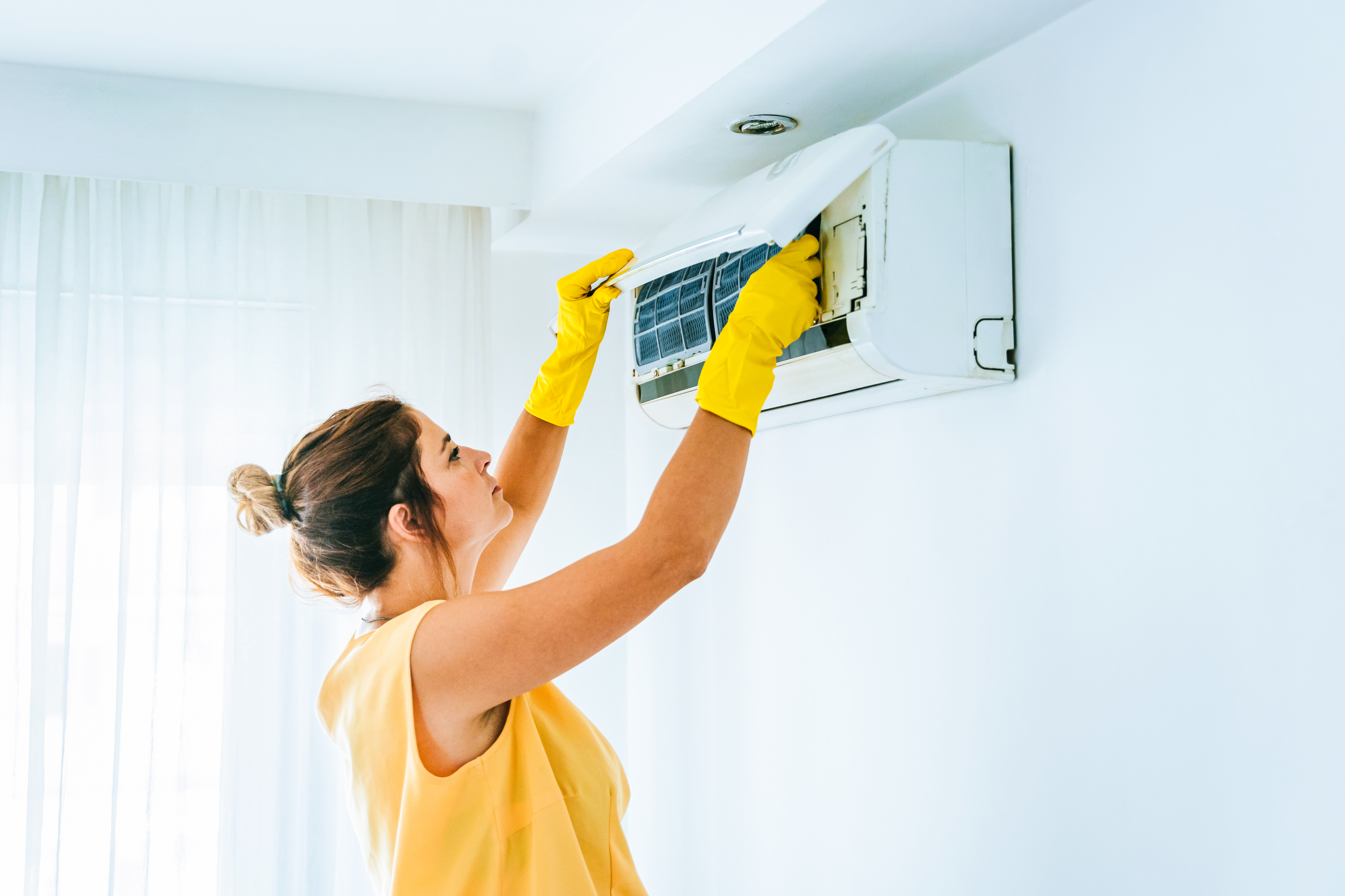 A woman cleans her heat pump filters