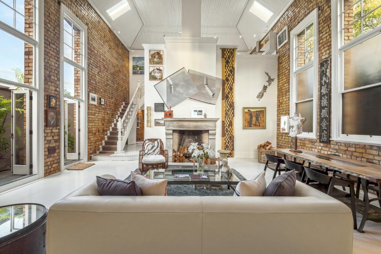 The ceiling soars more than 7m in the ground-floor living area. New doors (left) open to a narrow strip of land landscaped with palms. The floor was slightly elevated long ago, but the edge of the low stage can be seen at the bottom of the stairs (one of four stairs in the building). 