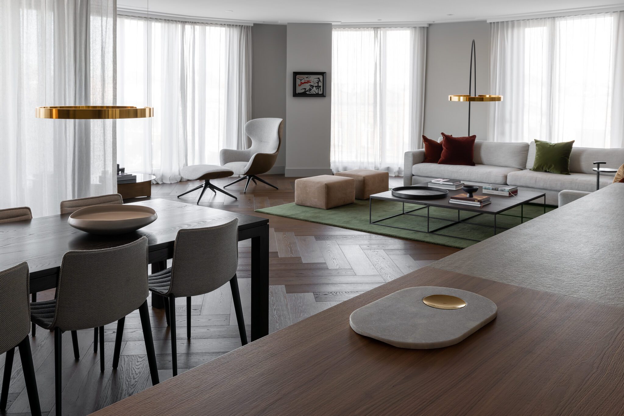 Modern open lounge/dining room with gold accents, minimalist with some pops of colour in the cushions.