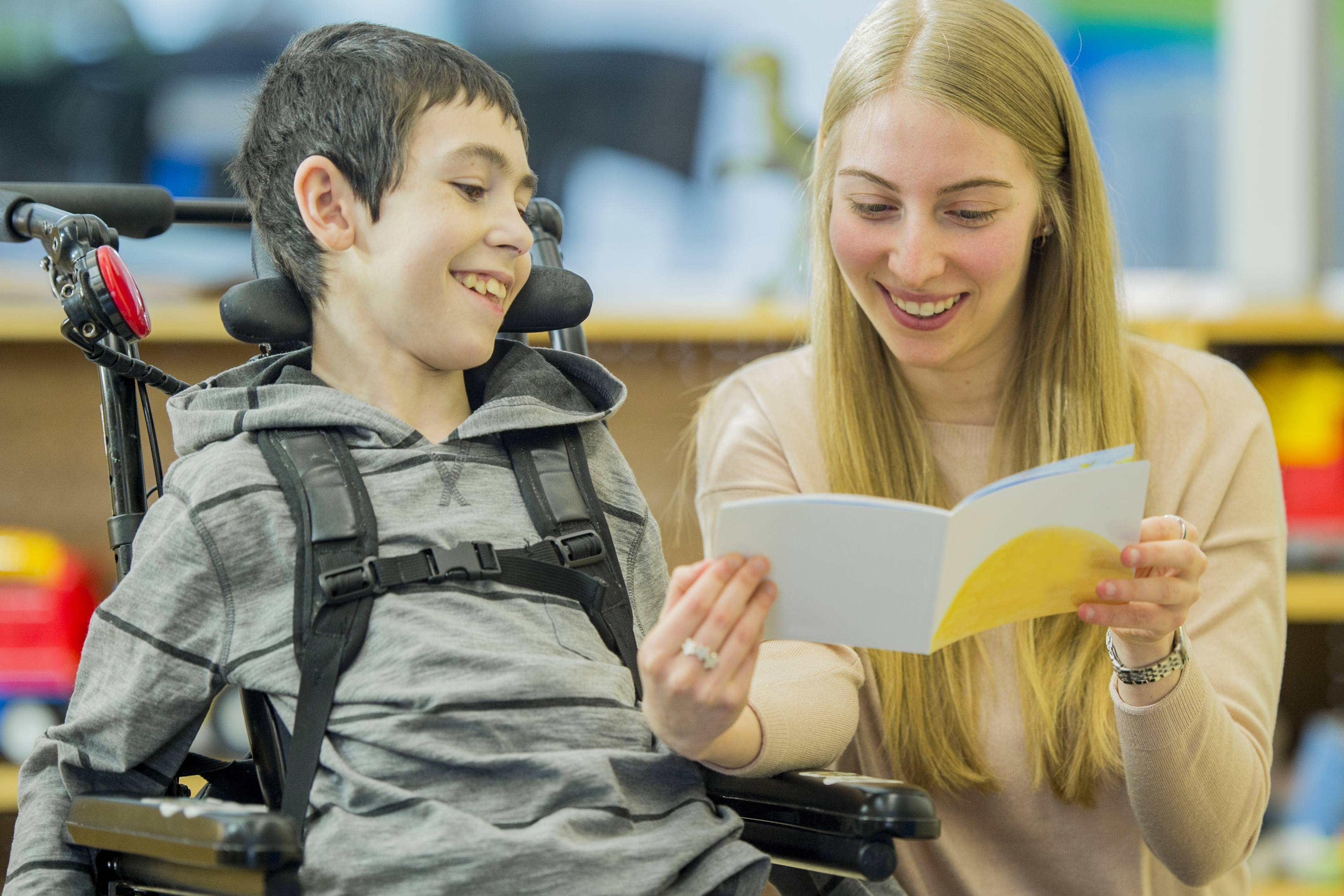 Teacher aide helping her student read a book