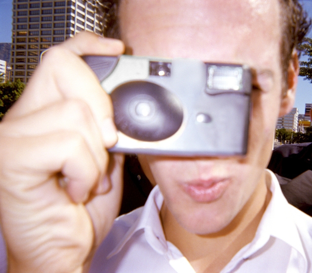 A man holding and using a disposable camera, capturing memories with analog photography.