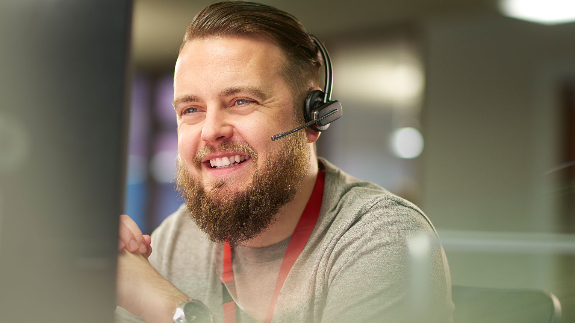 Smiling customer service agent sitting at a computer in his office.