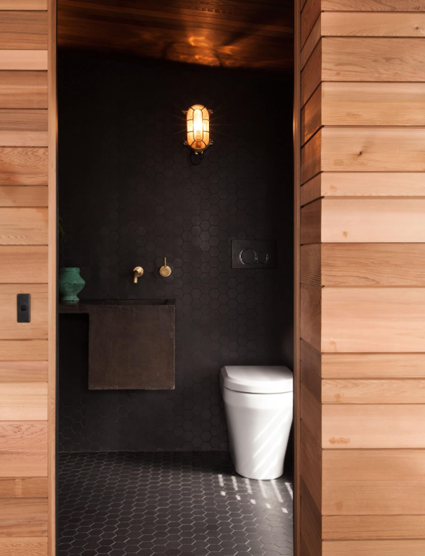 A wooden textural bathroom with black-painted walls and a richly textured floor, creating a warm and inviting atmosphere.