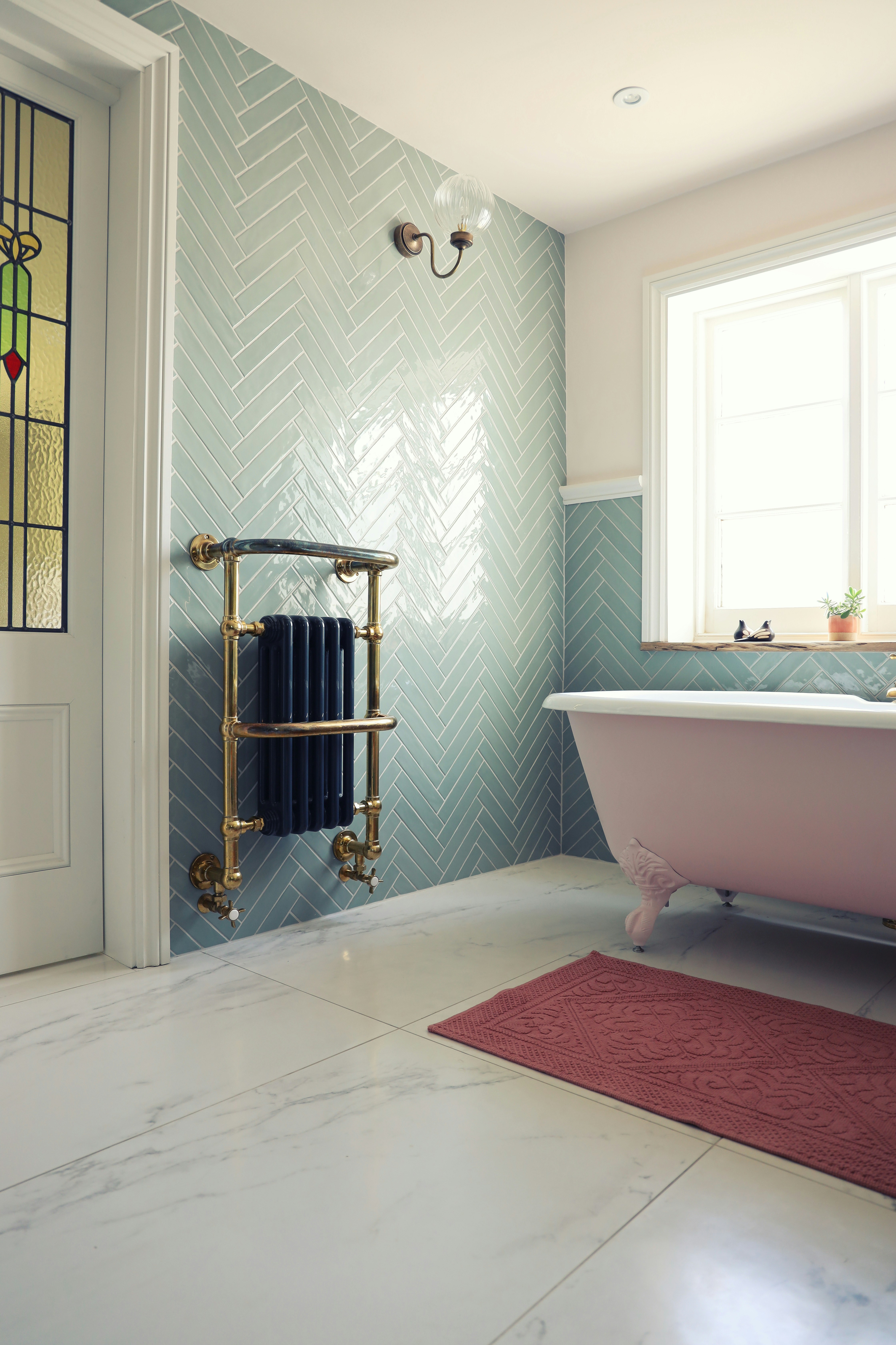 This traditional bathroom uses large-format floor tiles and wall tiles in a herringbone pattern, creating a layered aesthetic.