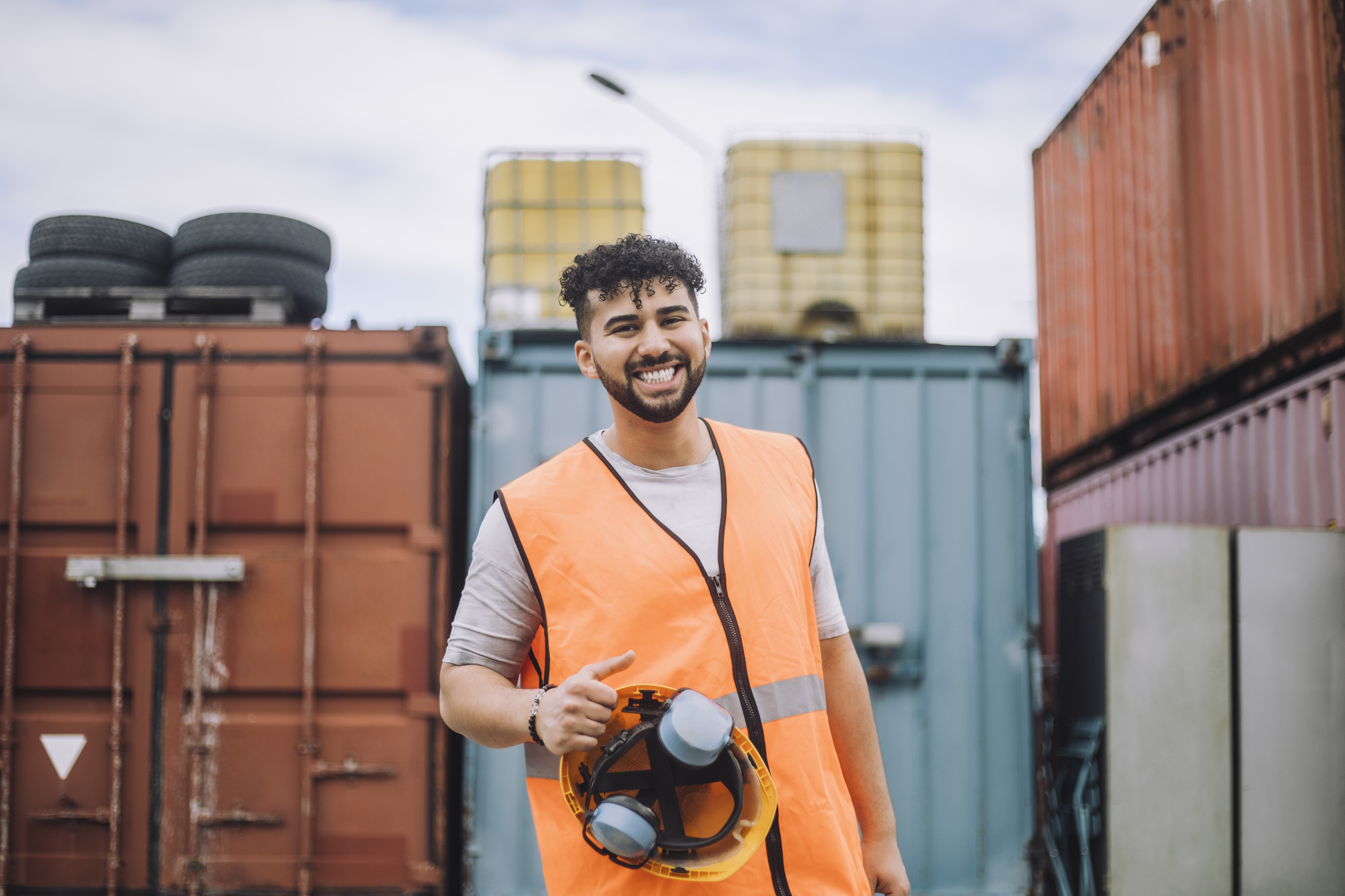 Man smiling while standing in front of shipping containers