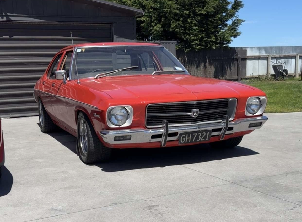 A red Holden photographed in an outdoor setting 