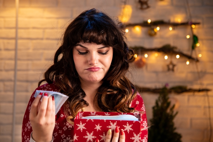 Woman opens a christmas gift box but doesn't look happy with the contents