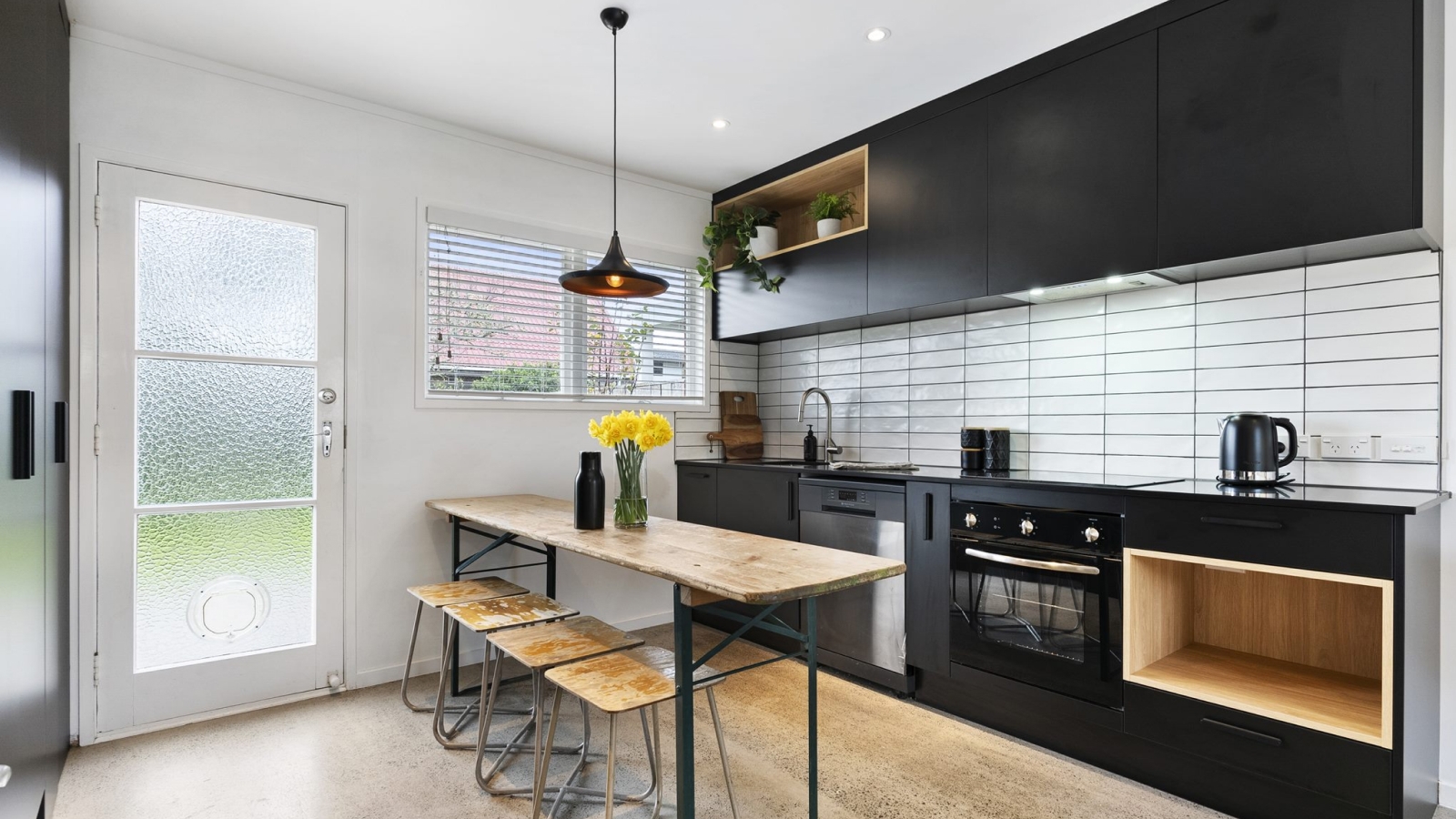 Industrial styled kitchen with black cabinetry and concrete floors.