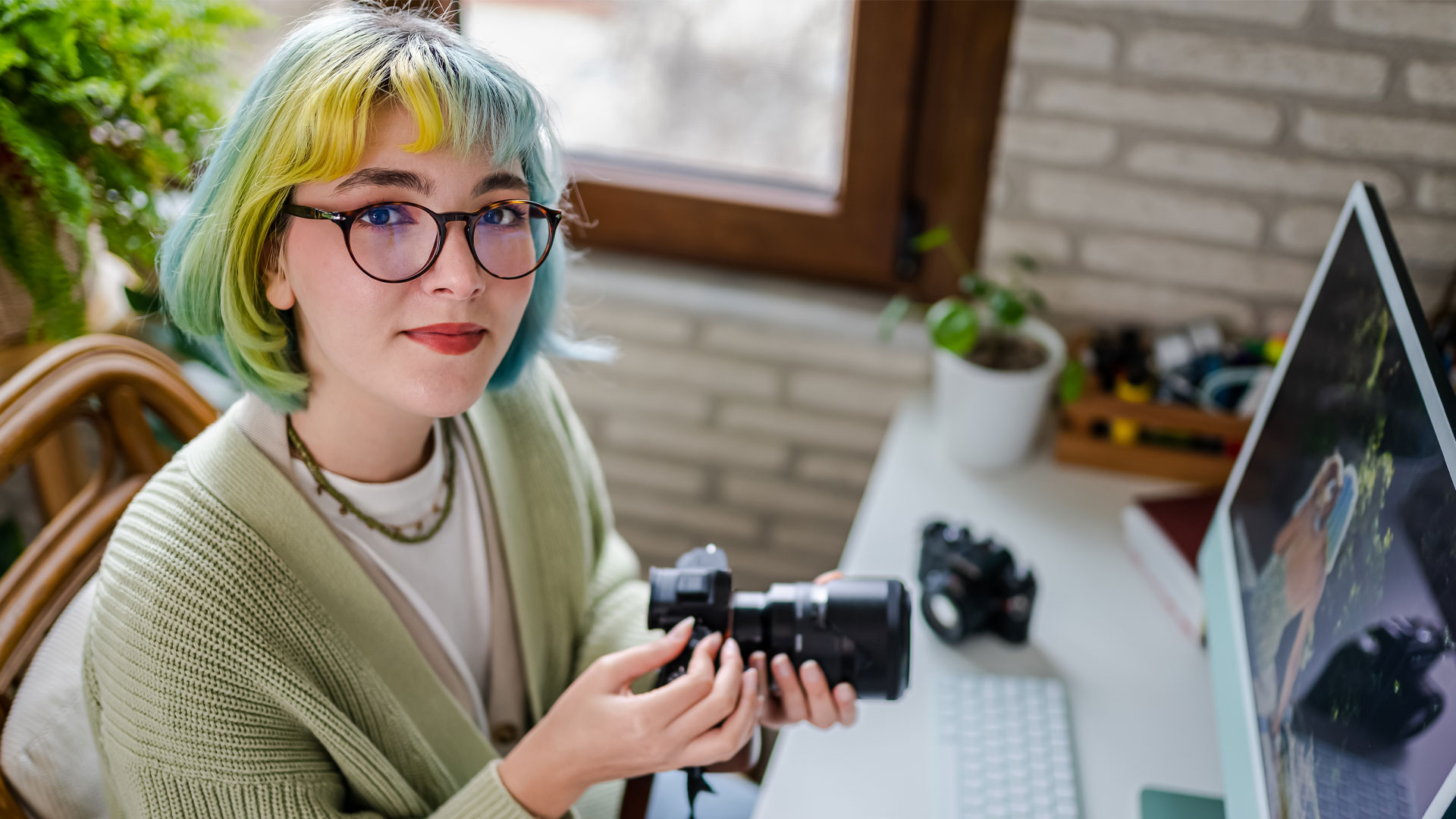 Freelance photographer holding a camera and editing photos on her laptop.