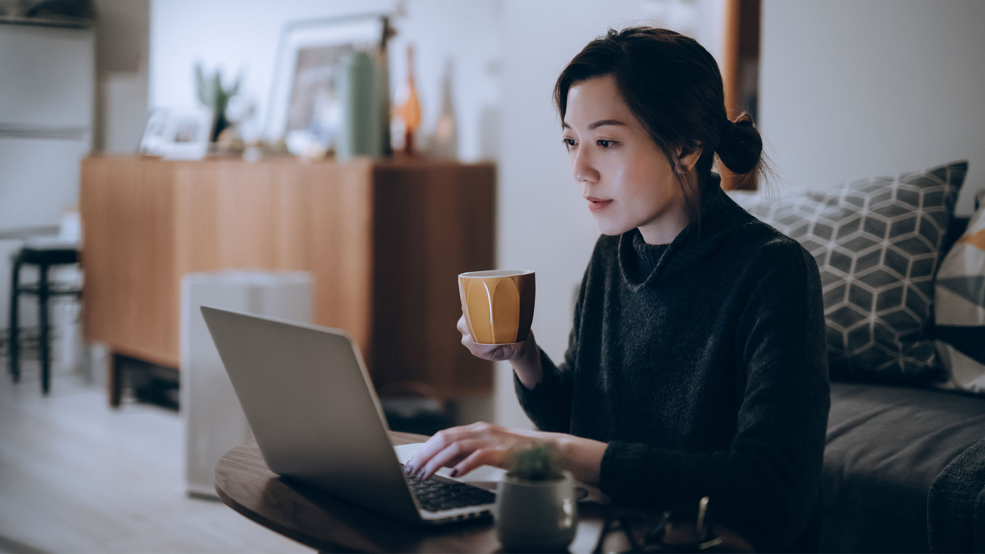 Young woman sitting at her laptop with a cup of coffee searching for jobs in NZ.