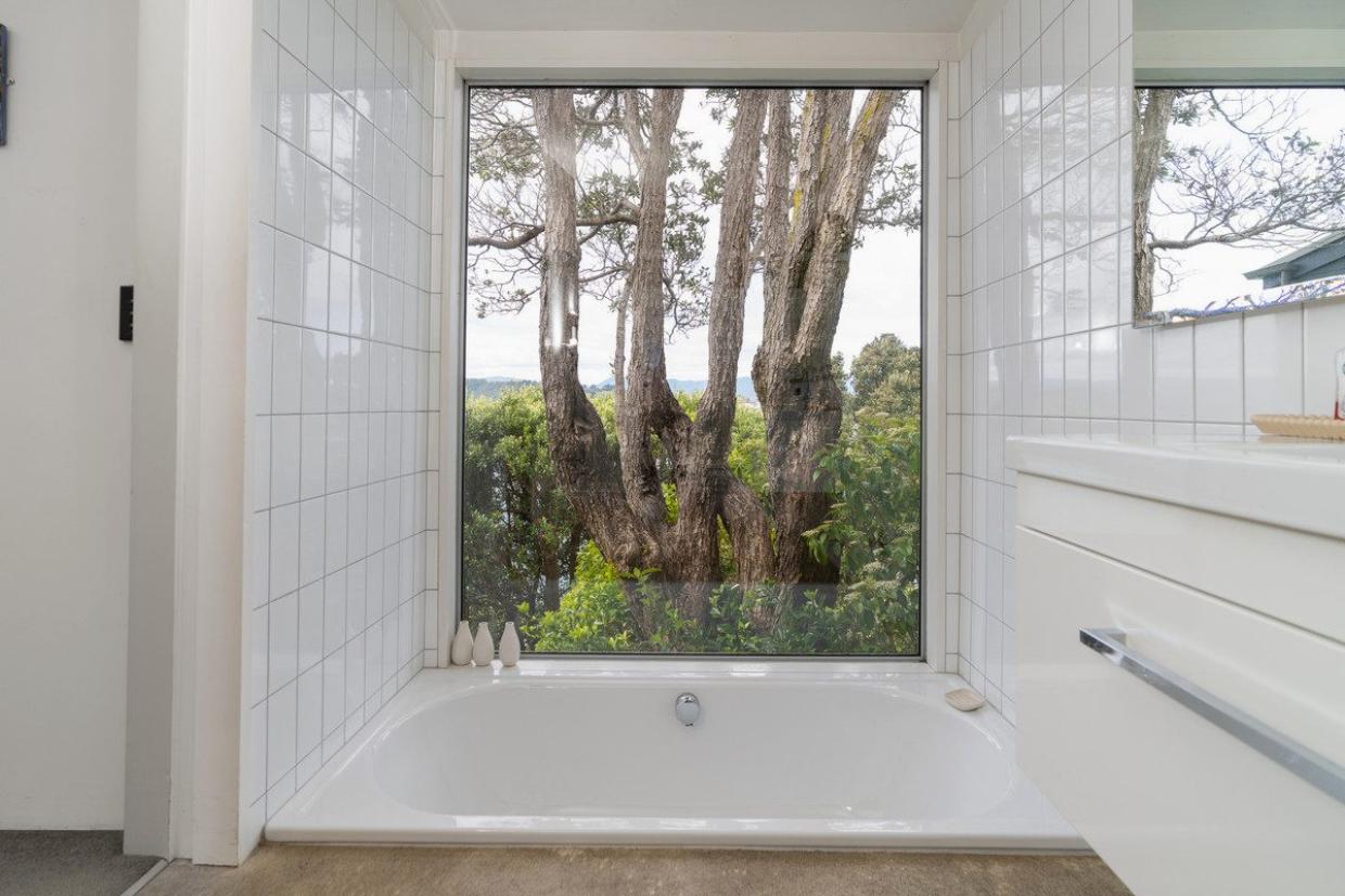 This bathroom frames a stunning view of a pōhutukawa. Photo: Lowe & Co