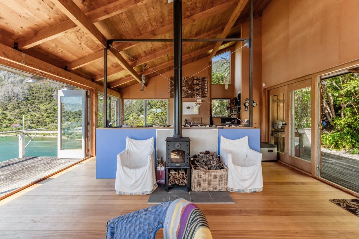 Eucalyptus flooring, macrocarpa sarking and beams, and unpainted walls give the open-plan living area a natural look that blends in with the native bush surroundings.