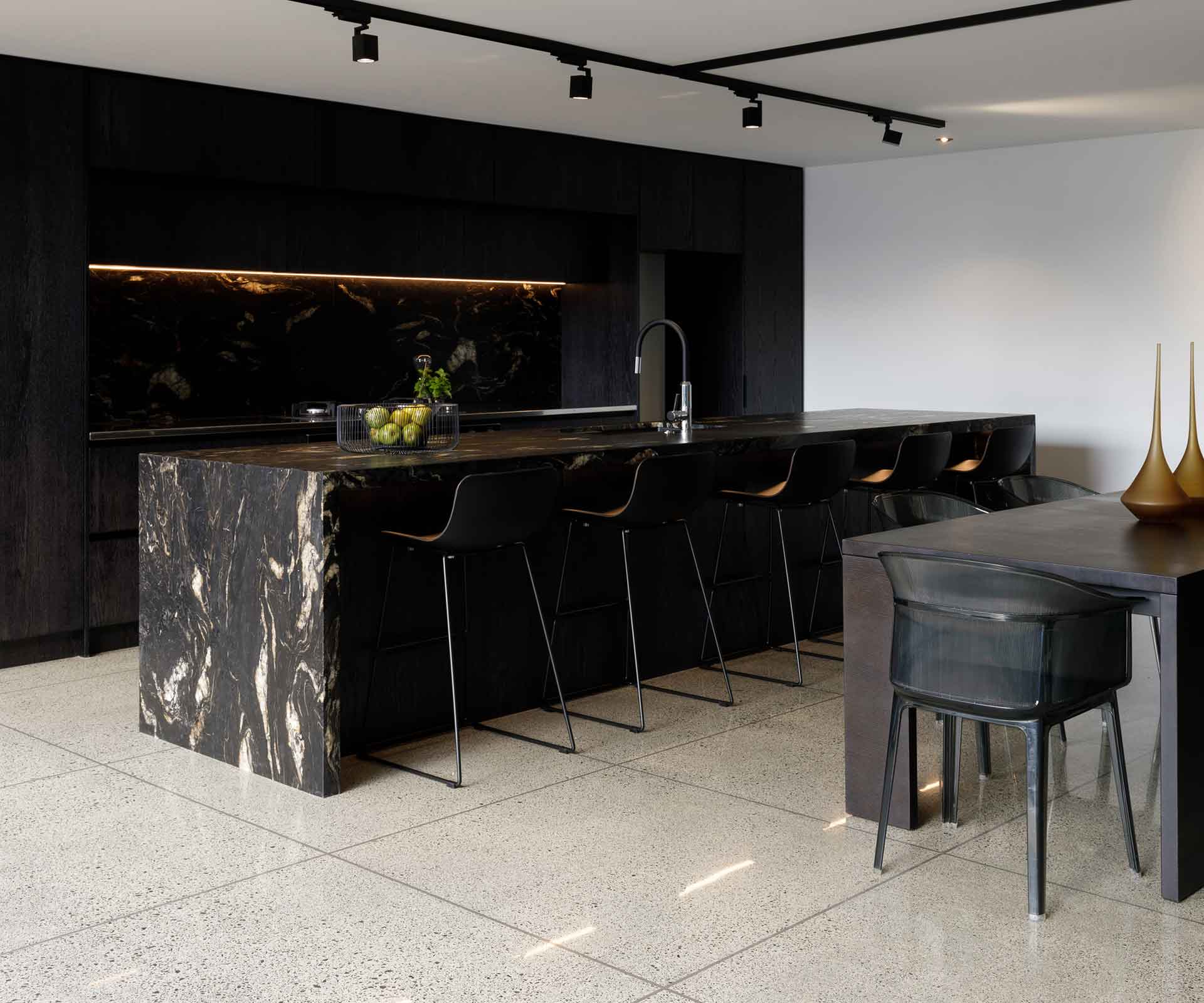 Wide angle kitchen shot with black marble counter and chairs