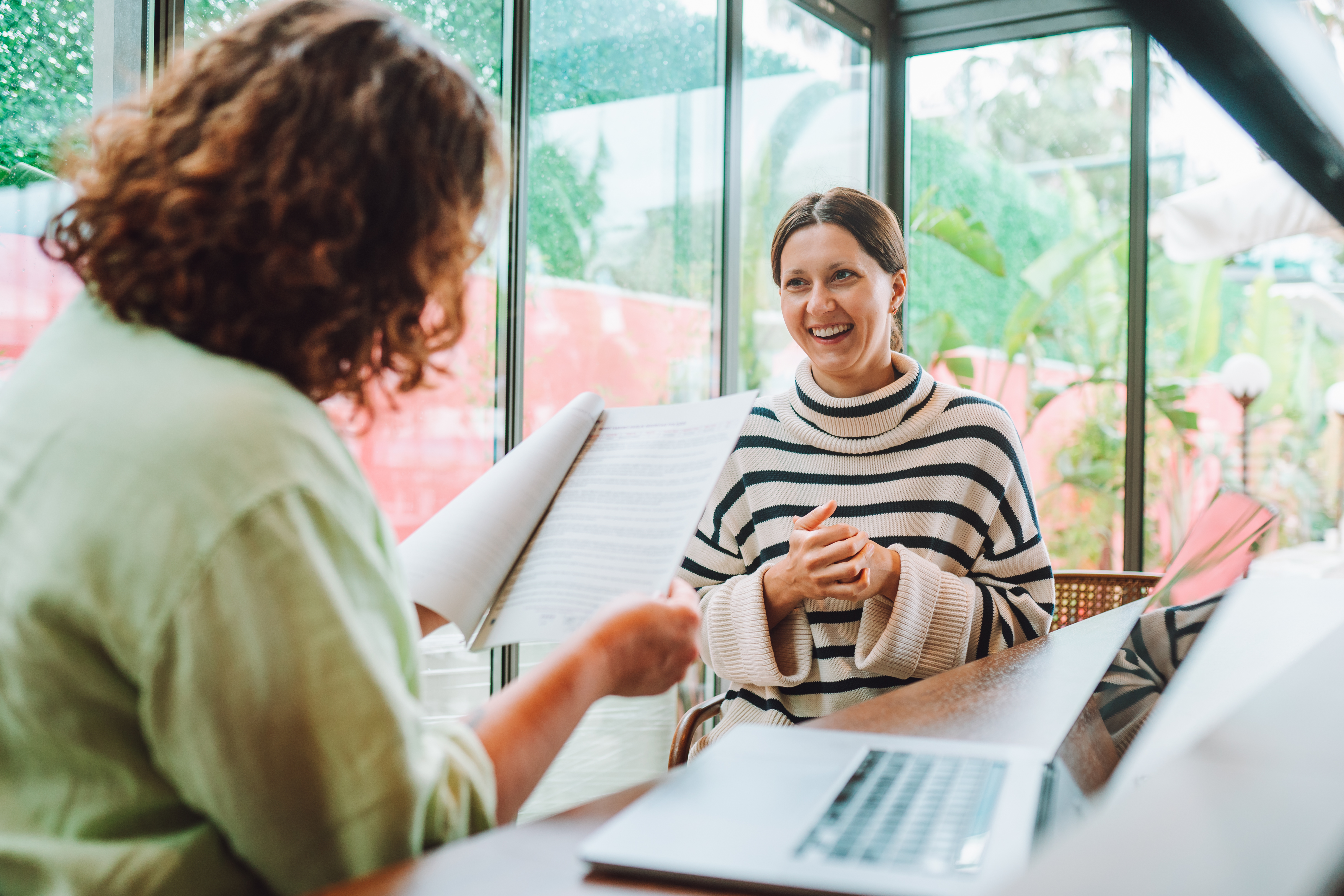 Woman sitting in an interview with interviewer looking over CV