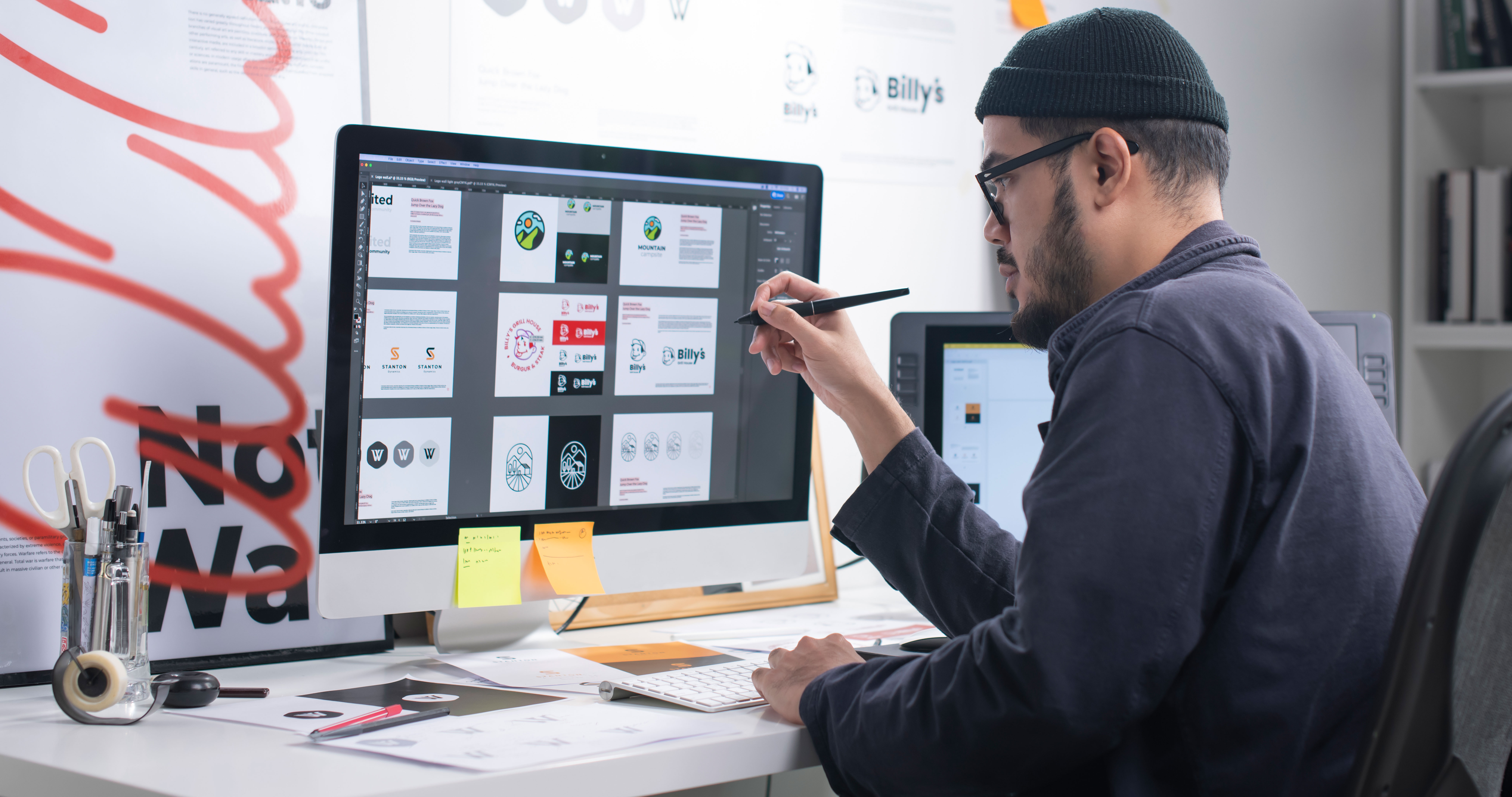 Graphic designer reviewing logos on a big monitor.