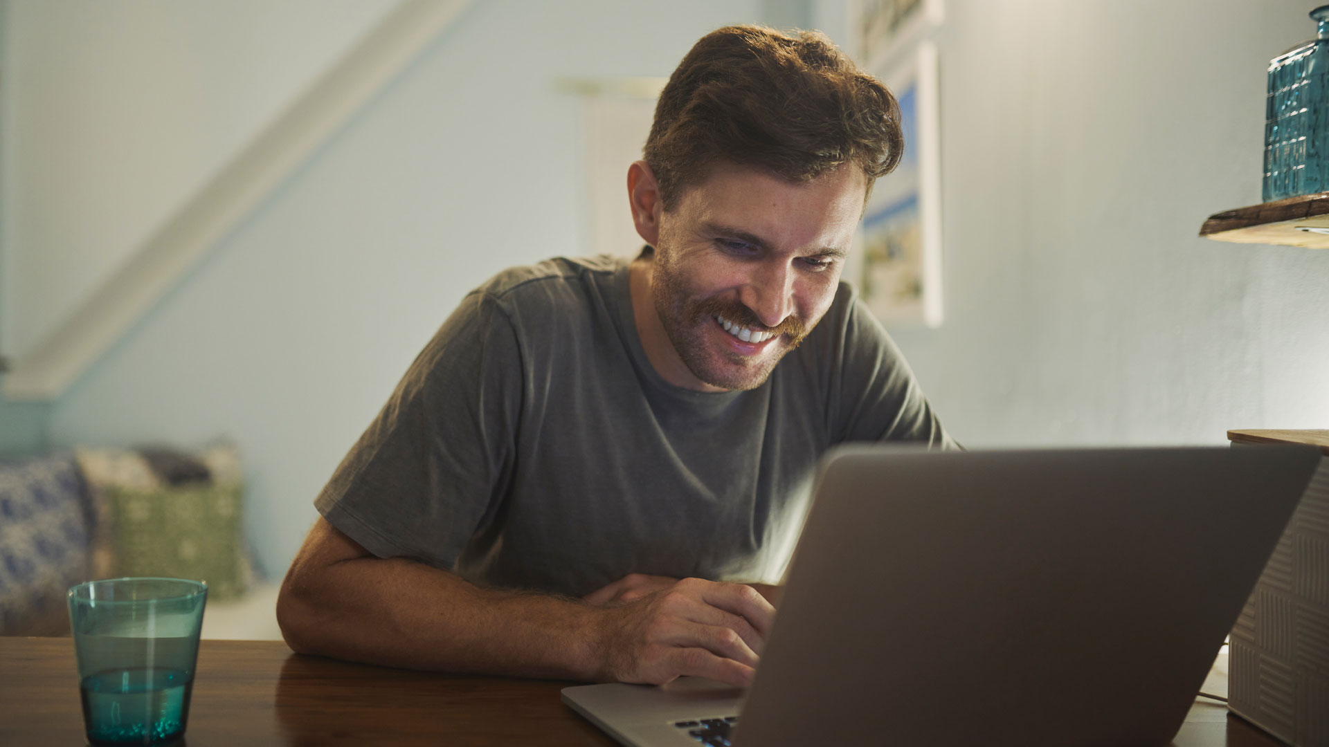 Man smiling at his laptop as he searches for jobs online.